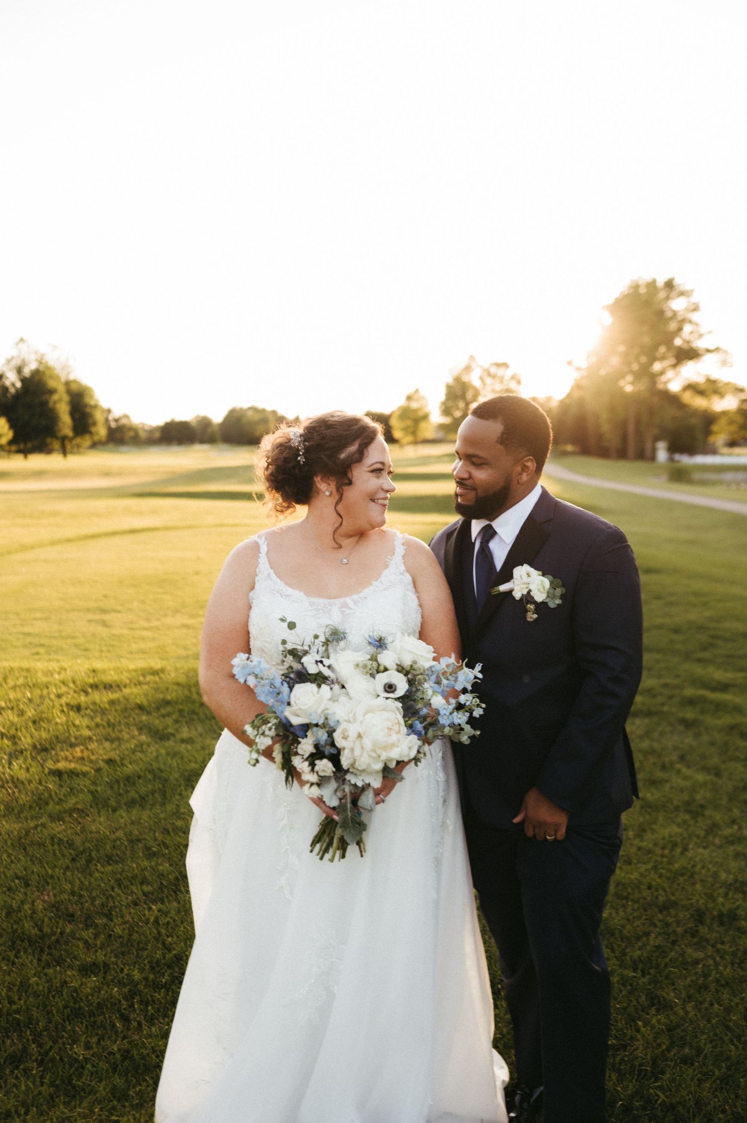Romantic sunset wedding portrait with beautiful white bouquet in an outdoor setting.