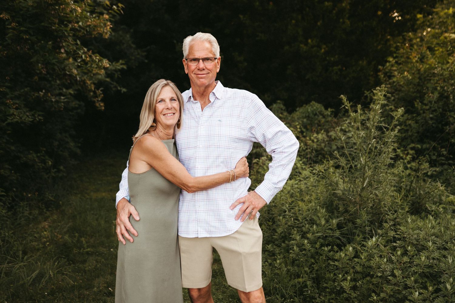 Affectionate group portrait with coordinated white and neutral outfits in a natural outdoor setting.
