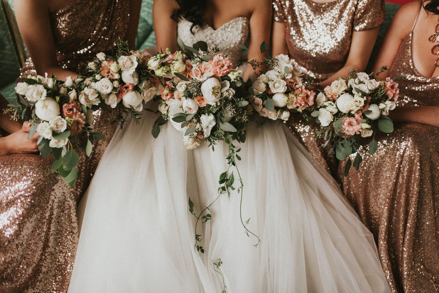 Bridesmaids holding elegant bouquets of blush and white flowers alongside a bride in a white tulle gown.