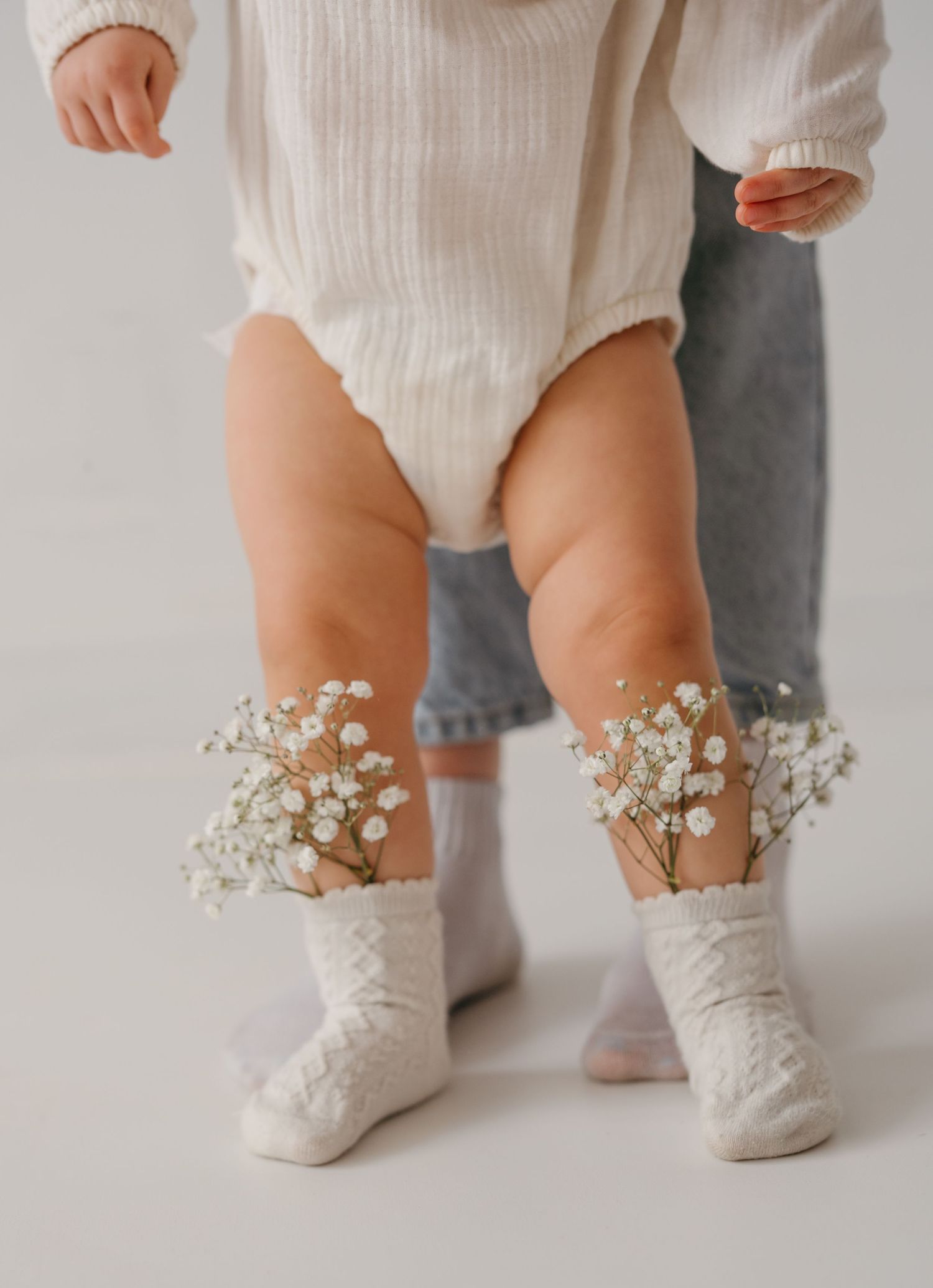 Baby feet wearing delicate white socks decorated with tiny baby's breath flowers.