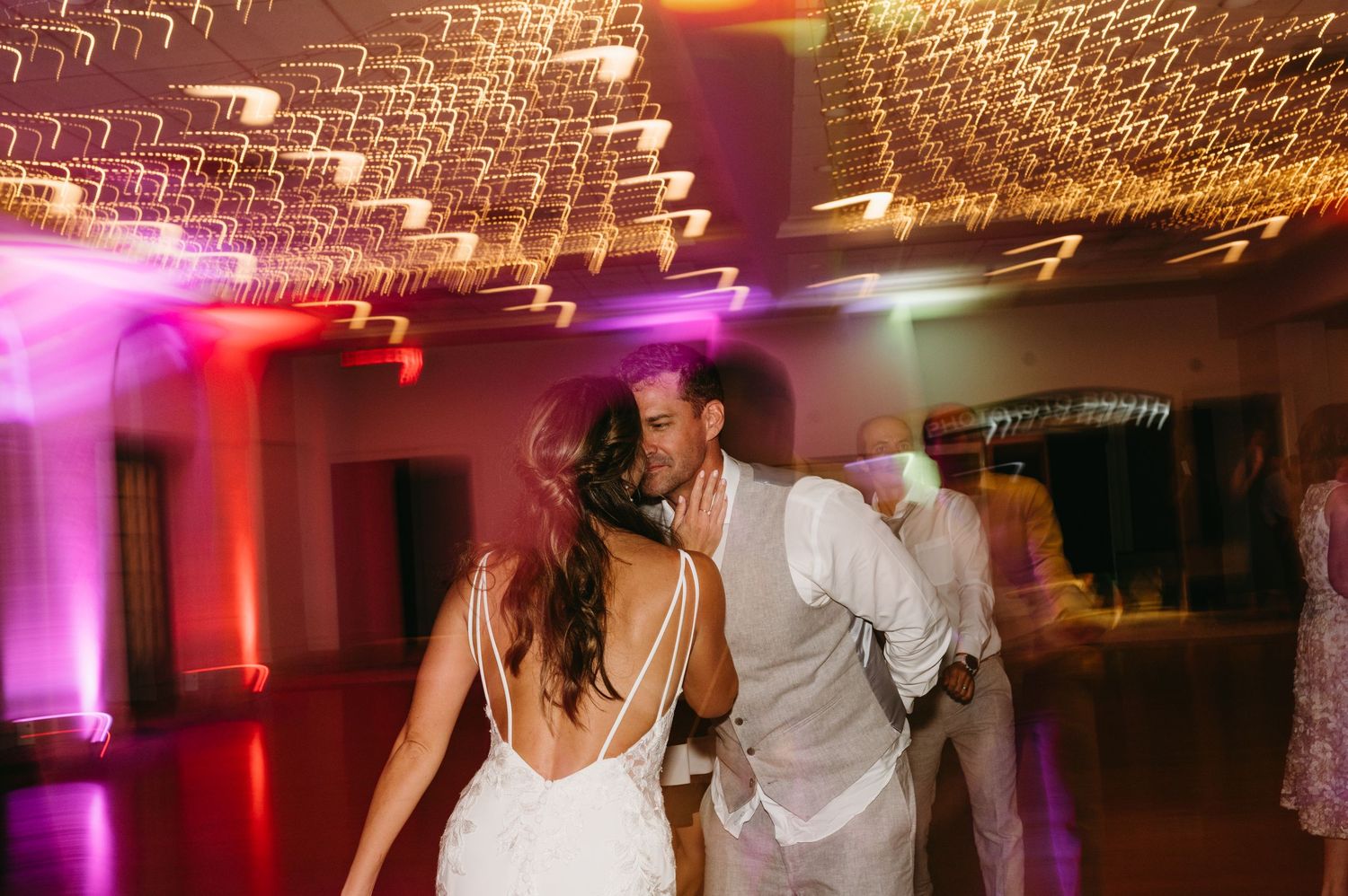Couple dancing at their wedding reception under romantic lighting and sparkle effects.