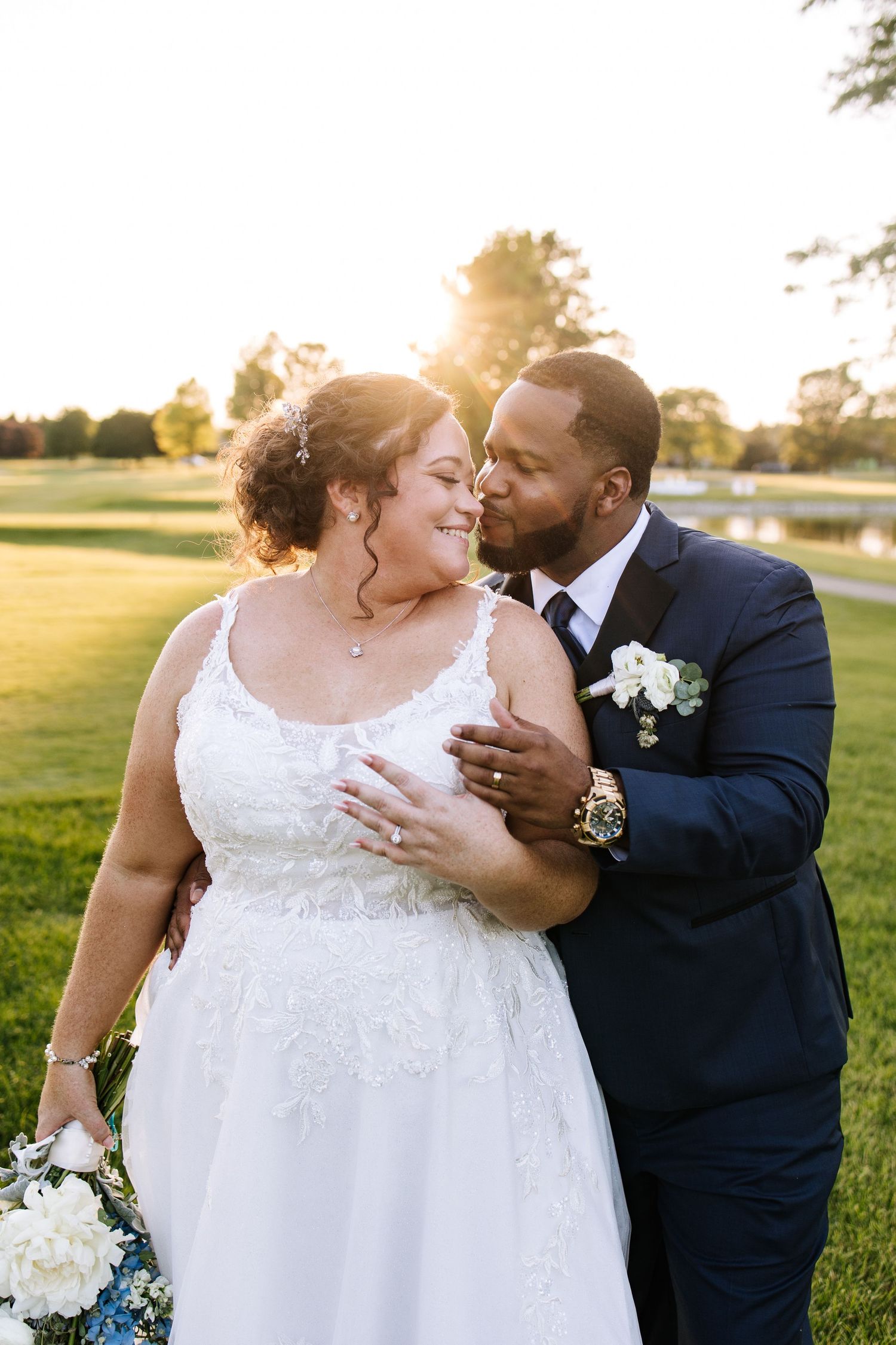 Romantic outdoor wedding photos of newlyweds embracing in a sunlit field at golden hour.