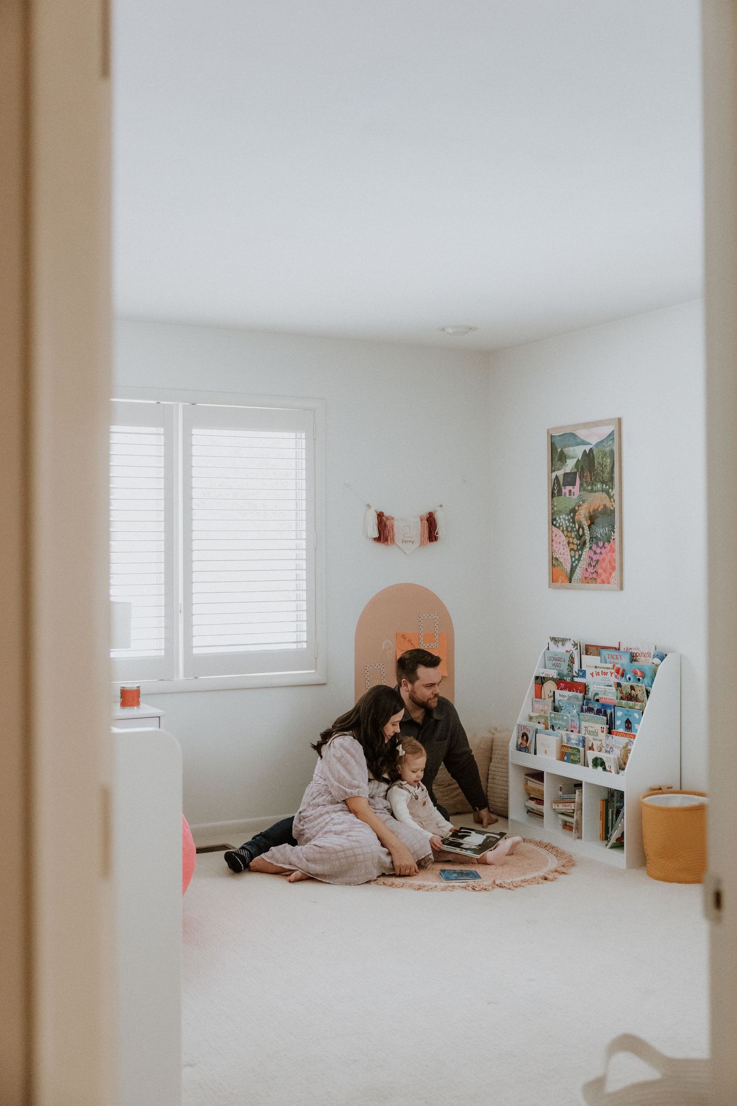 A cozy reading nook scene with bookshelves and colorful wall art in a bright white room.