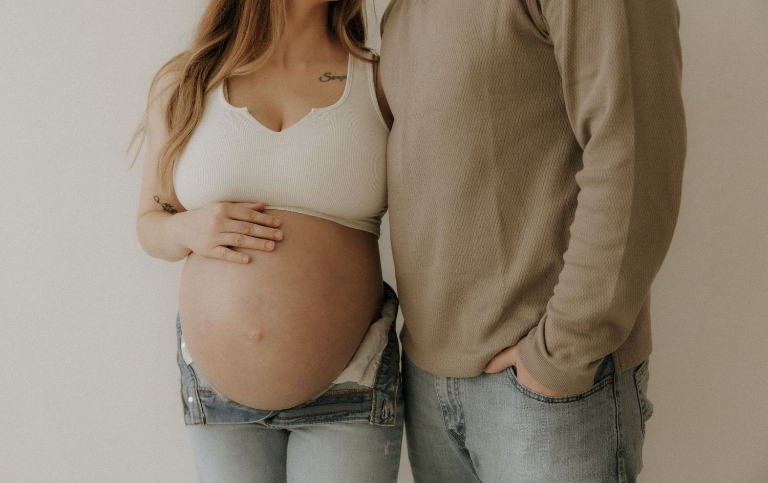 A series of intimate maternity photos showing a couple embracing while wearing neutral-colored casual clothing.