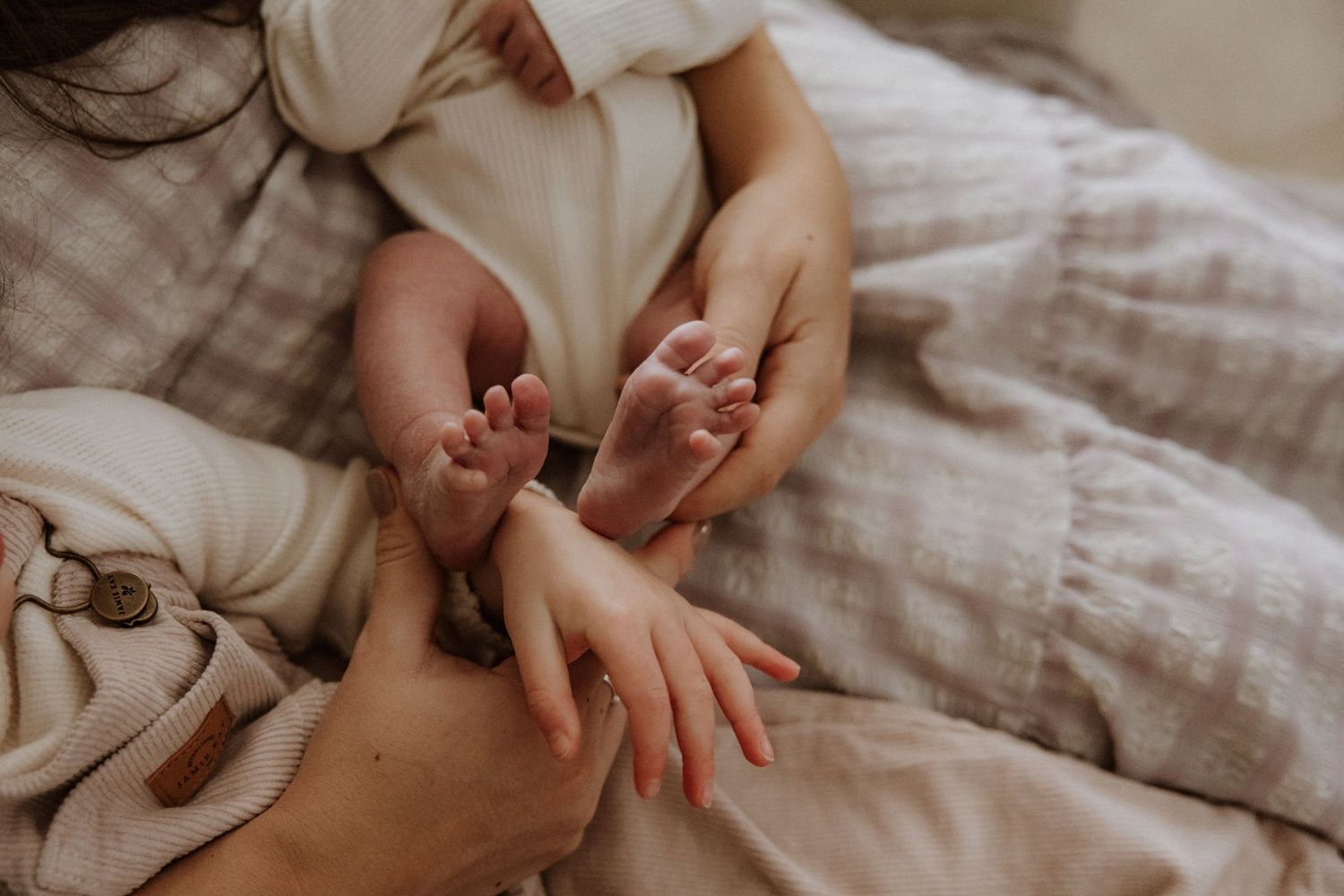 Hands gently hold and fold soft white linens or bedding material on a textured surface.