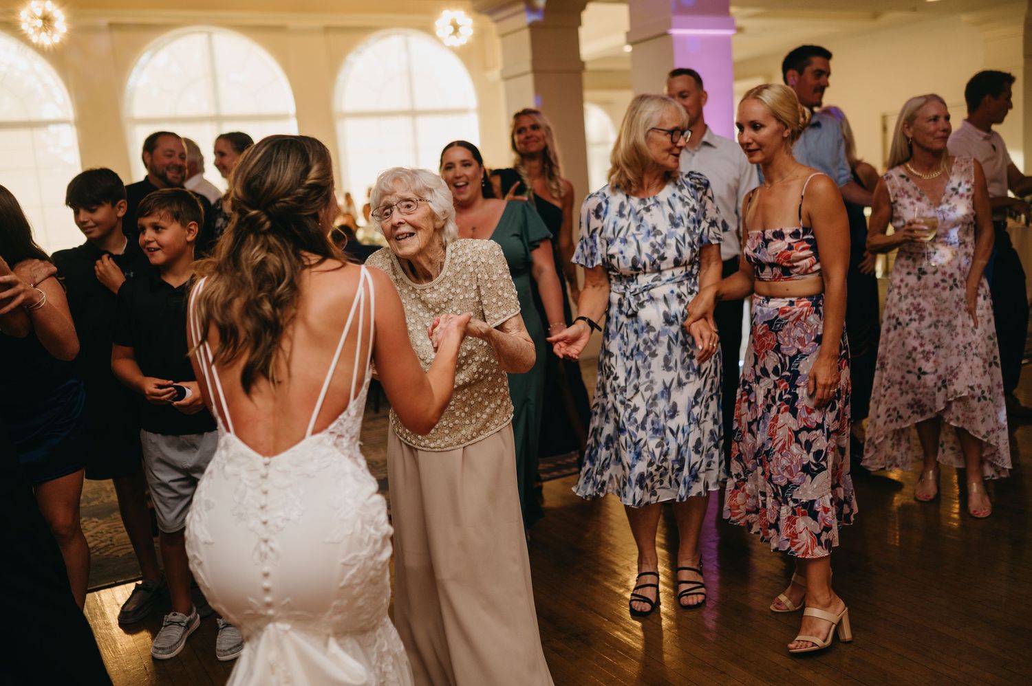 Wedding reception dance party with guests celebrating on a crowded dance floor under indoor lighting.