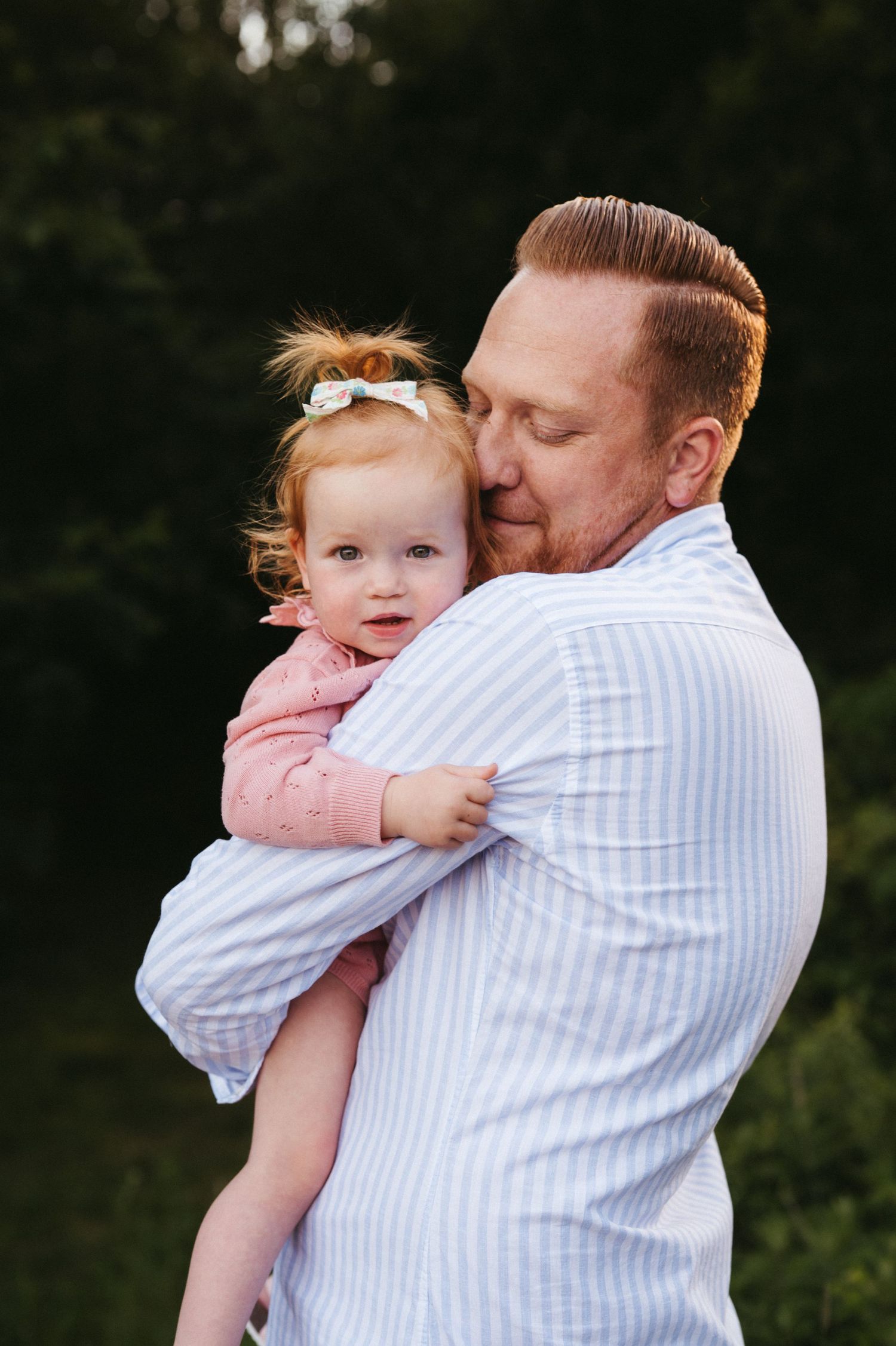 Tender moment between parent and child during outdoor portrait session at golden hour.