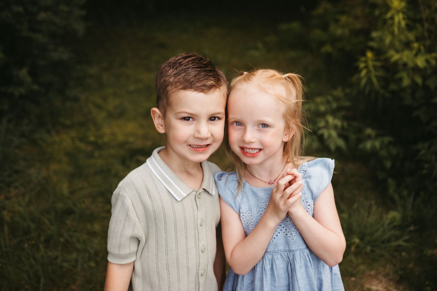 Children share playful moment together during outdoor portrait session in natural setting.