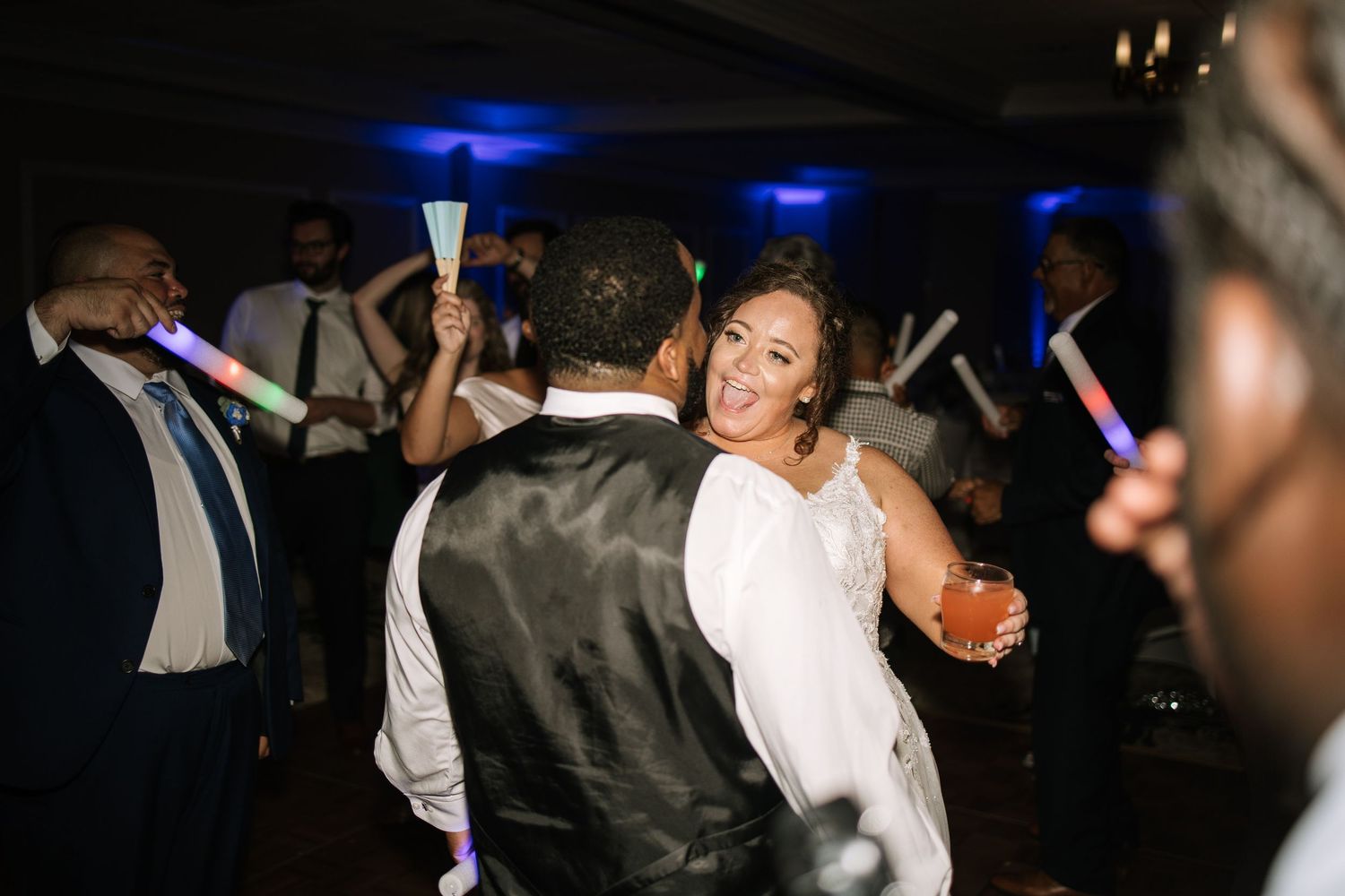 Energetic dance floor scene at wedding reception with blue lighting and motion blur.