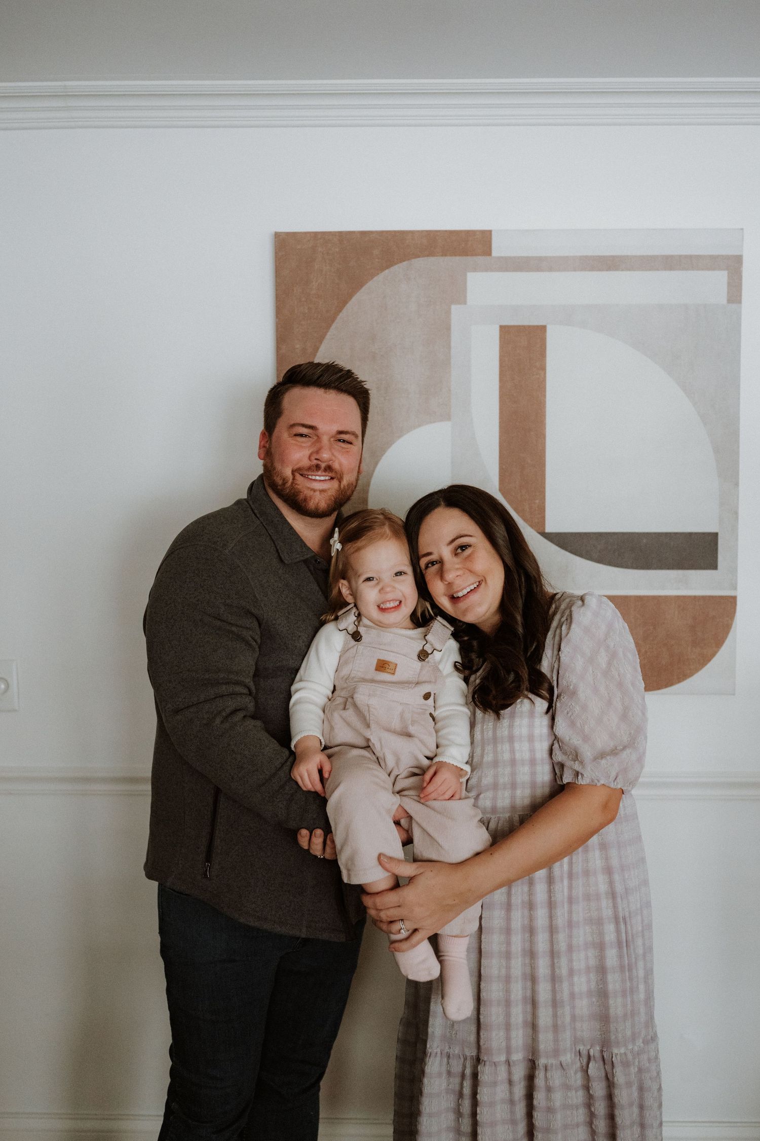 A family photo series against a white wall showing parents and children in coordinated neutral-toned outfits.