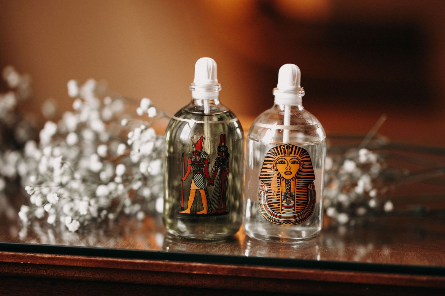Two decorative glass perfume bottles with baby's breath flowers on wooden surface.
