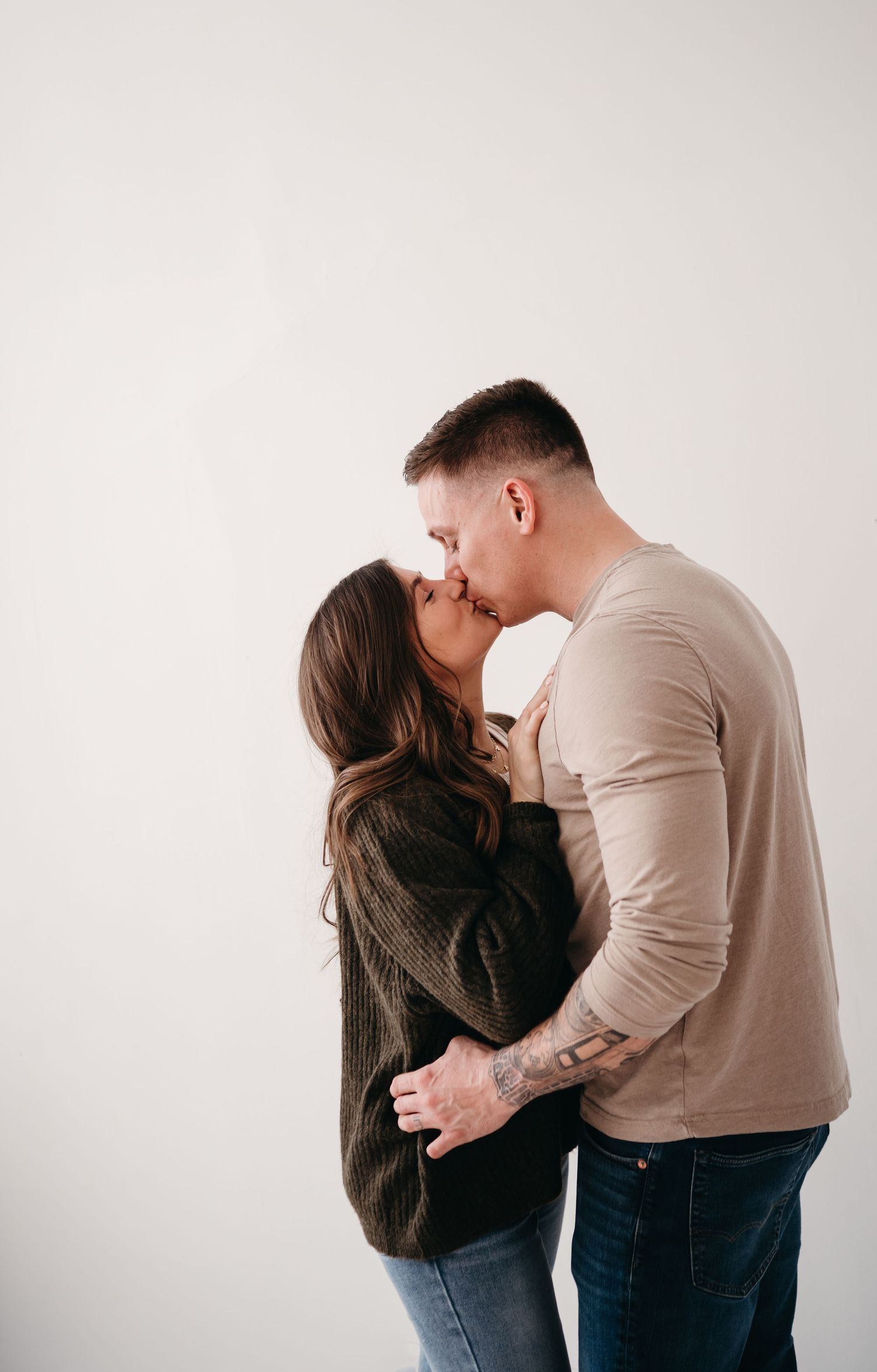 Romantic couple sharing tender kiss against minimalist white background.