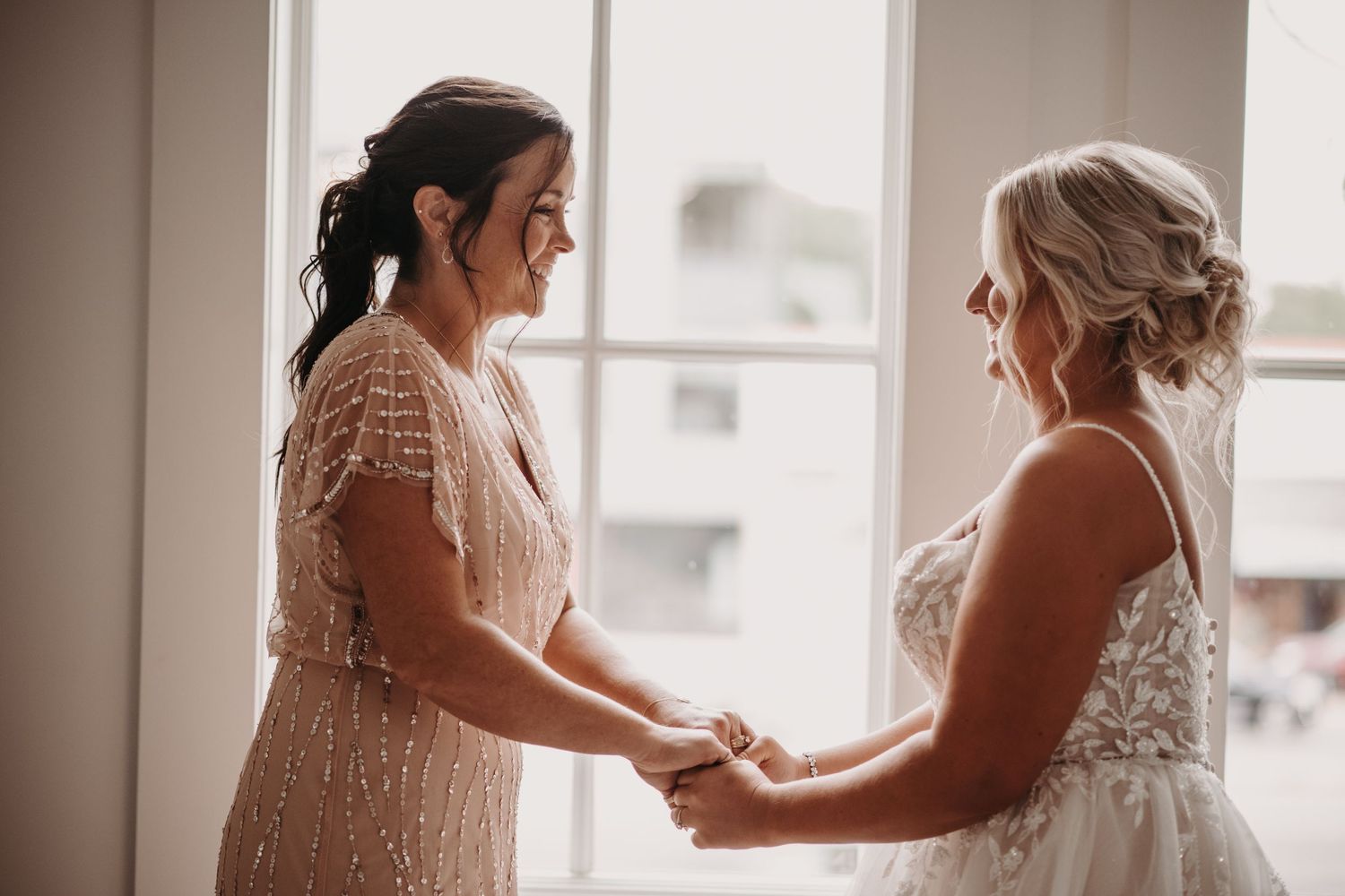 Emotional moment shared between two people in formal attire during wedding preparations.