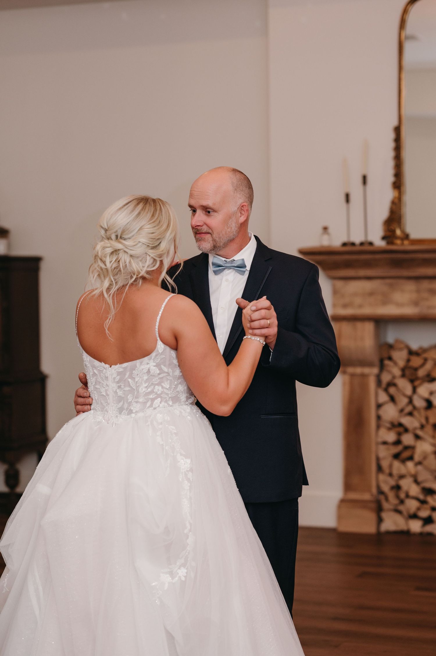 Intimate first dance moment in an elegant room with hardwood floors and fireplace.