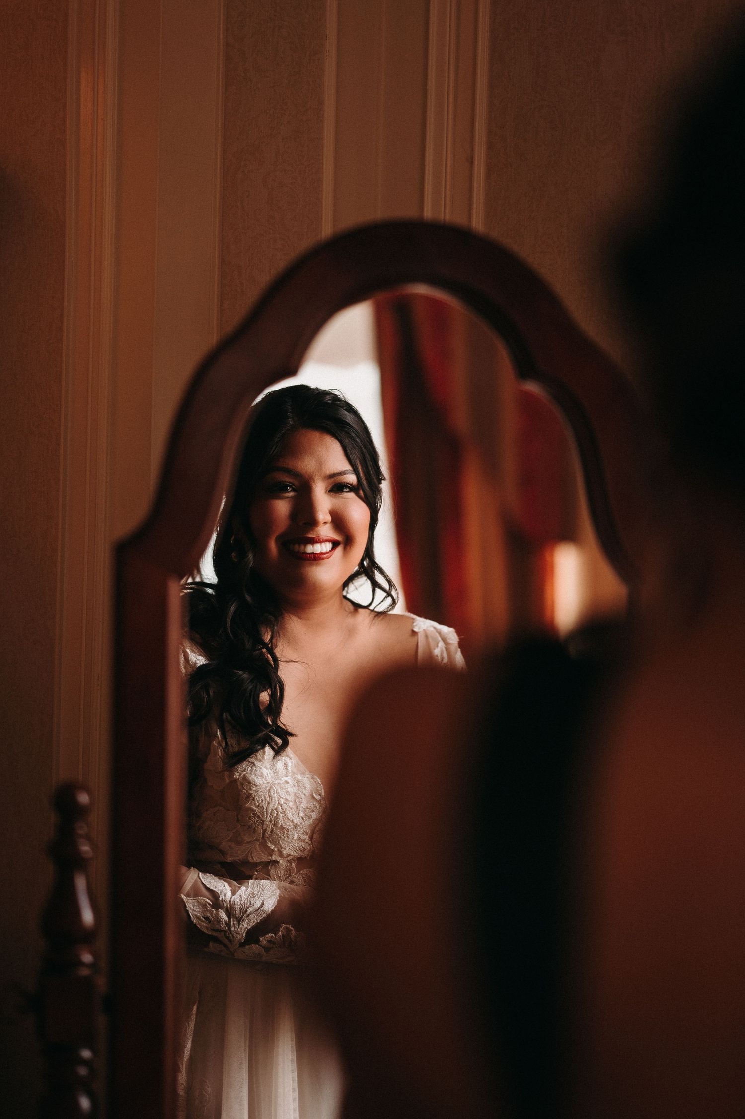 Candid mirror reflection captures joyful moment in bridal preparation.