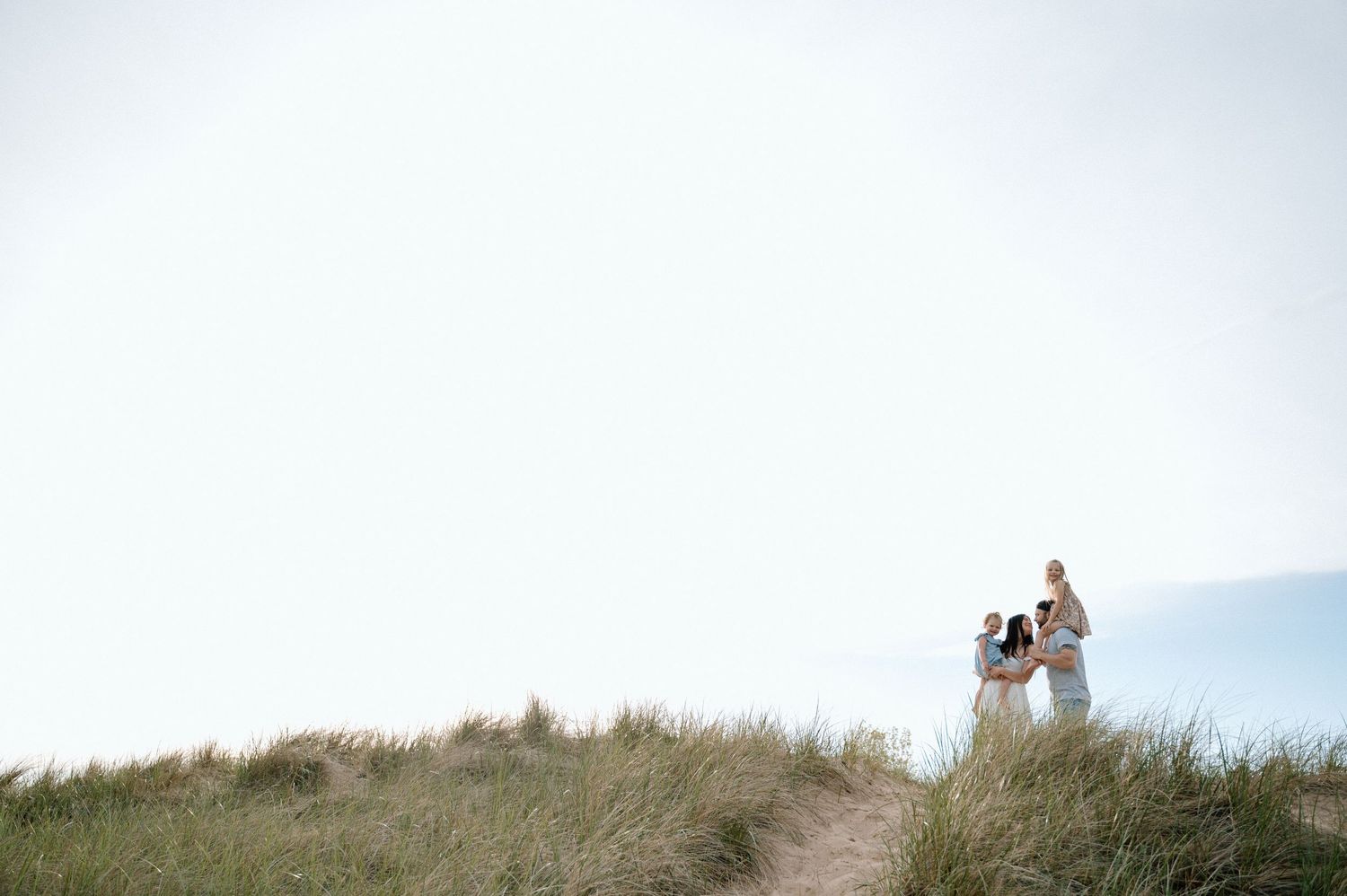 Distant figures stand on a grassy hilltop against a bright sky.