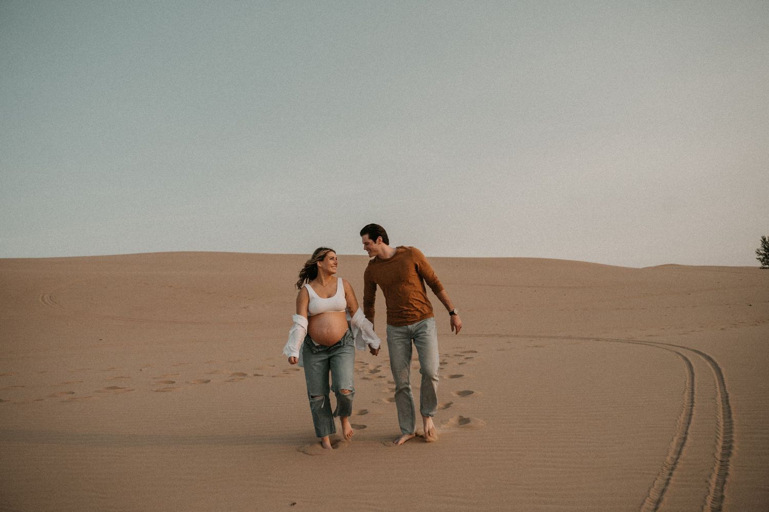 Two people walking together on sandy dunes during a desert photoshoot.