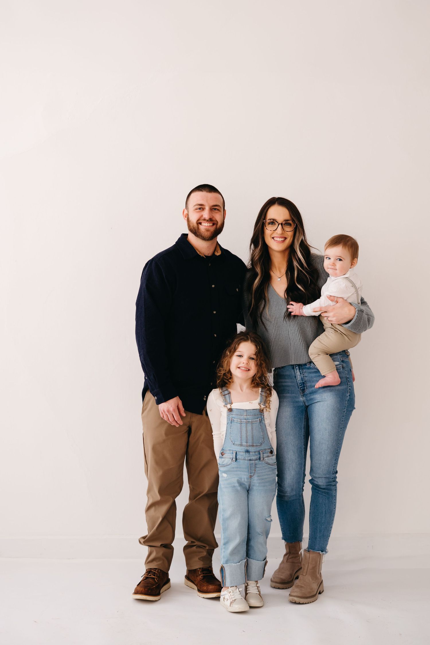 Full-length portrait of family in casual wear standing against white background.
