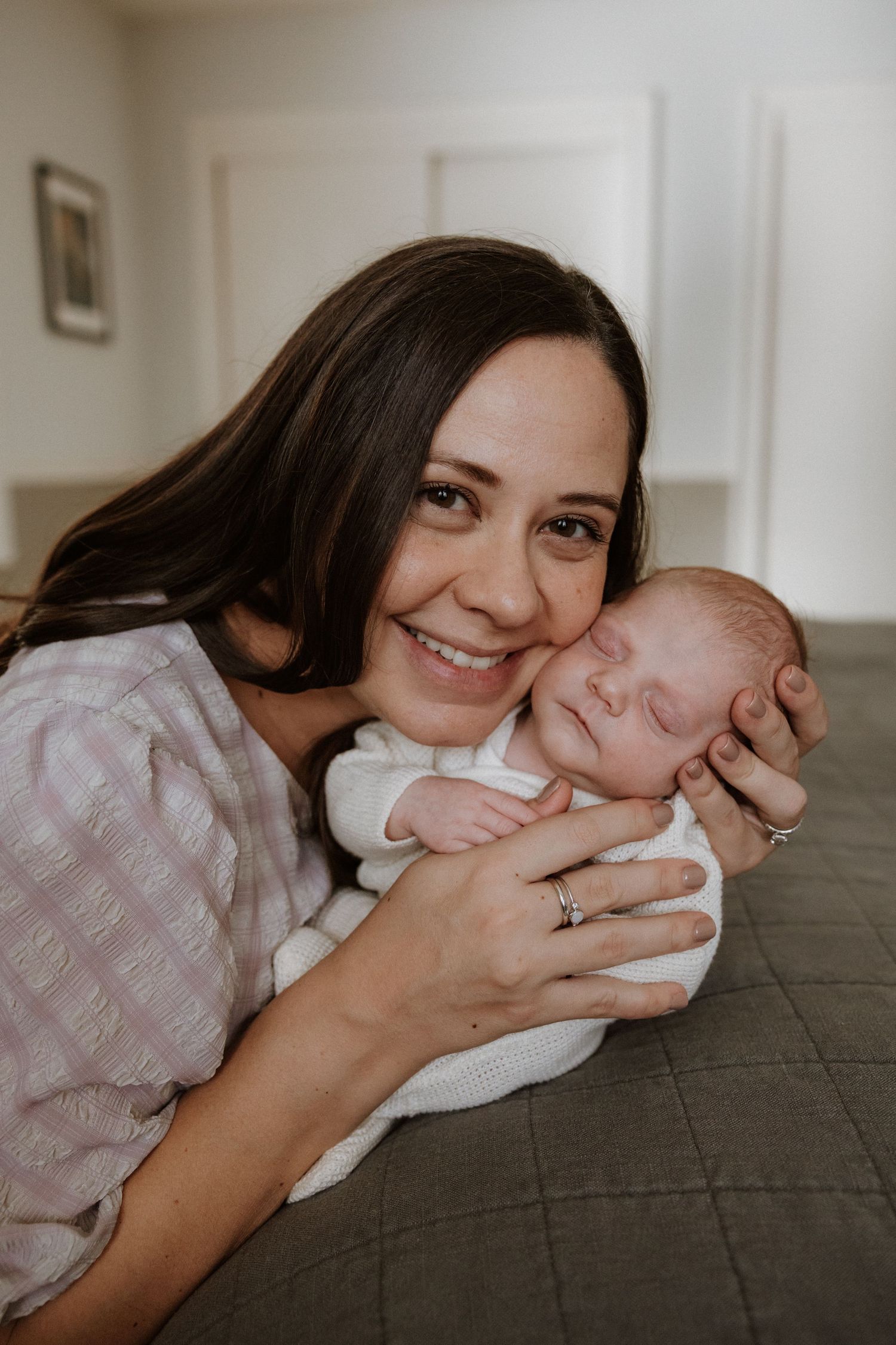 Tender family moment with newborn baby resting on soft couch.