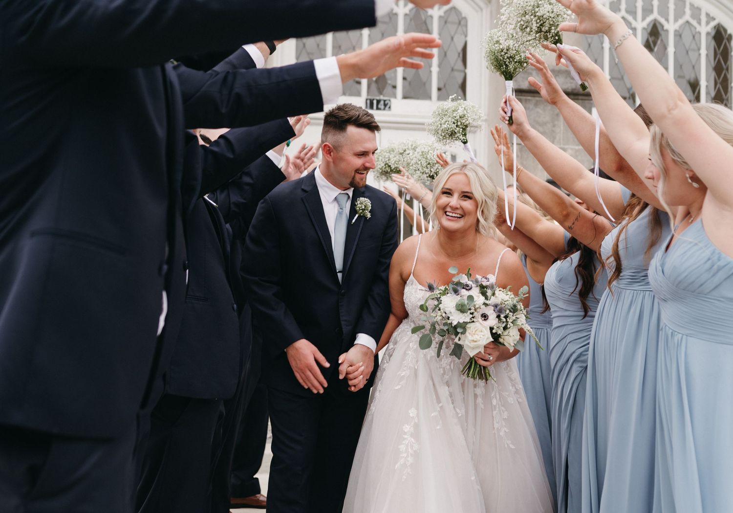 Joyful celebration moment with wedding party outside historic church building.