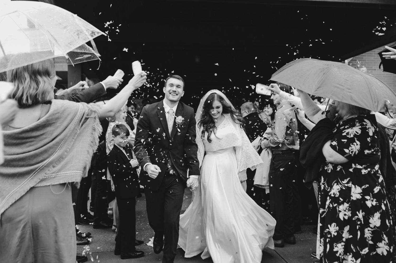 Wedding guests toss confetti during outdoor celebration.