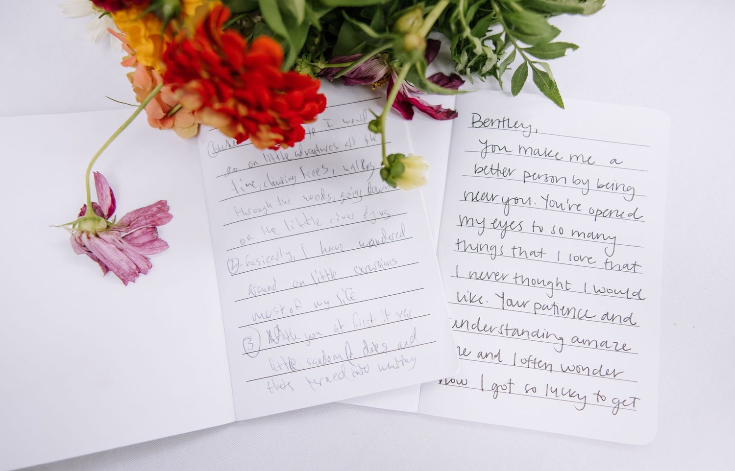 Handwritten wedding vows with delicate flower petals scattered across the pages.