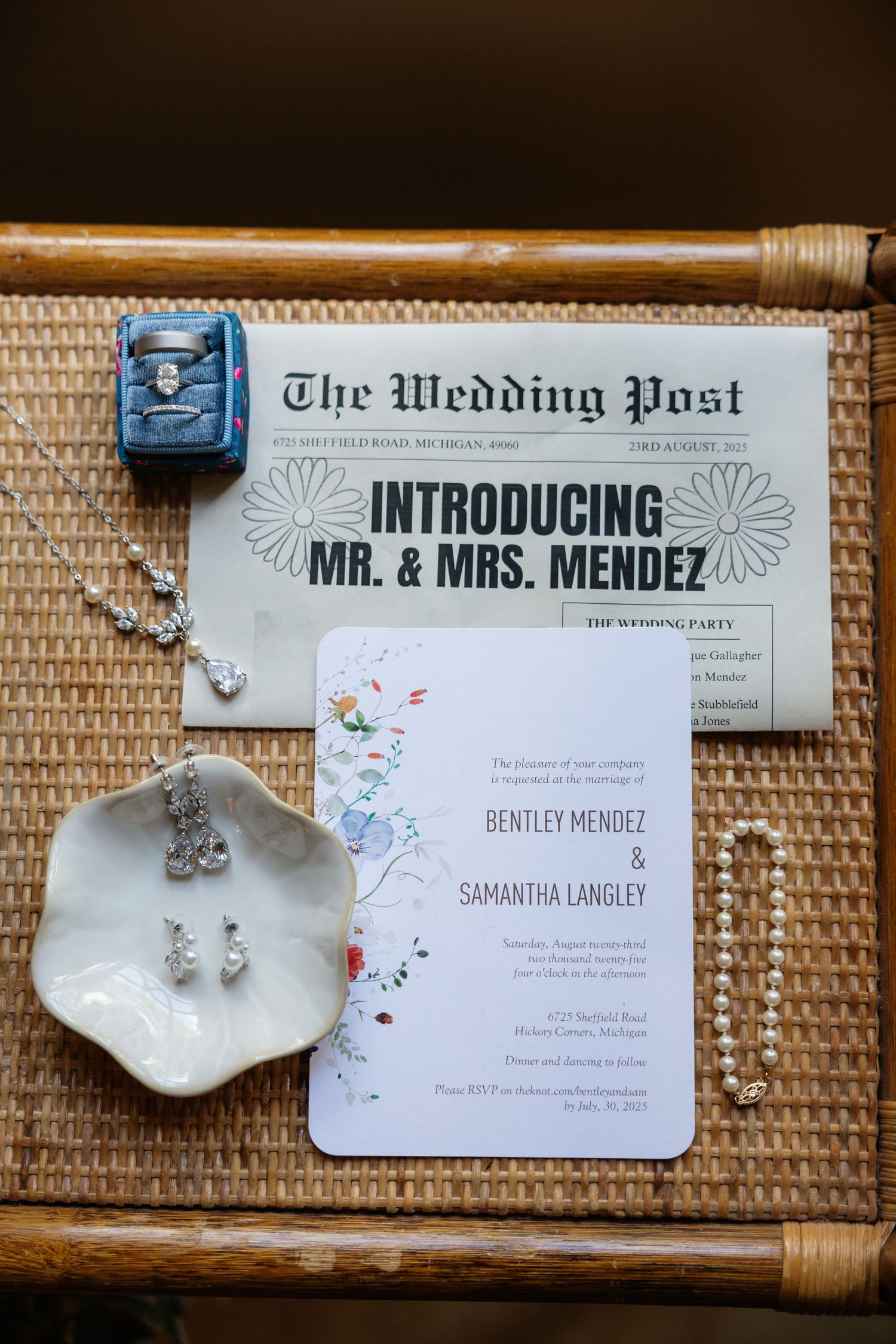 Wedding stationery and jewelry displayed on textured bamboo background.