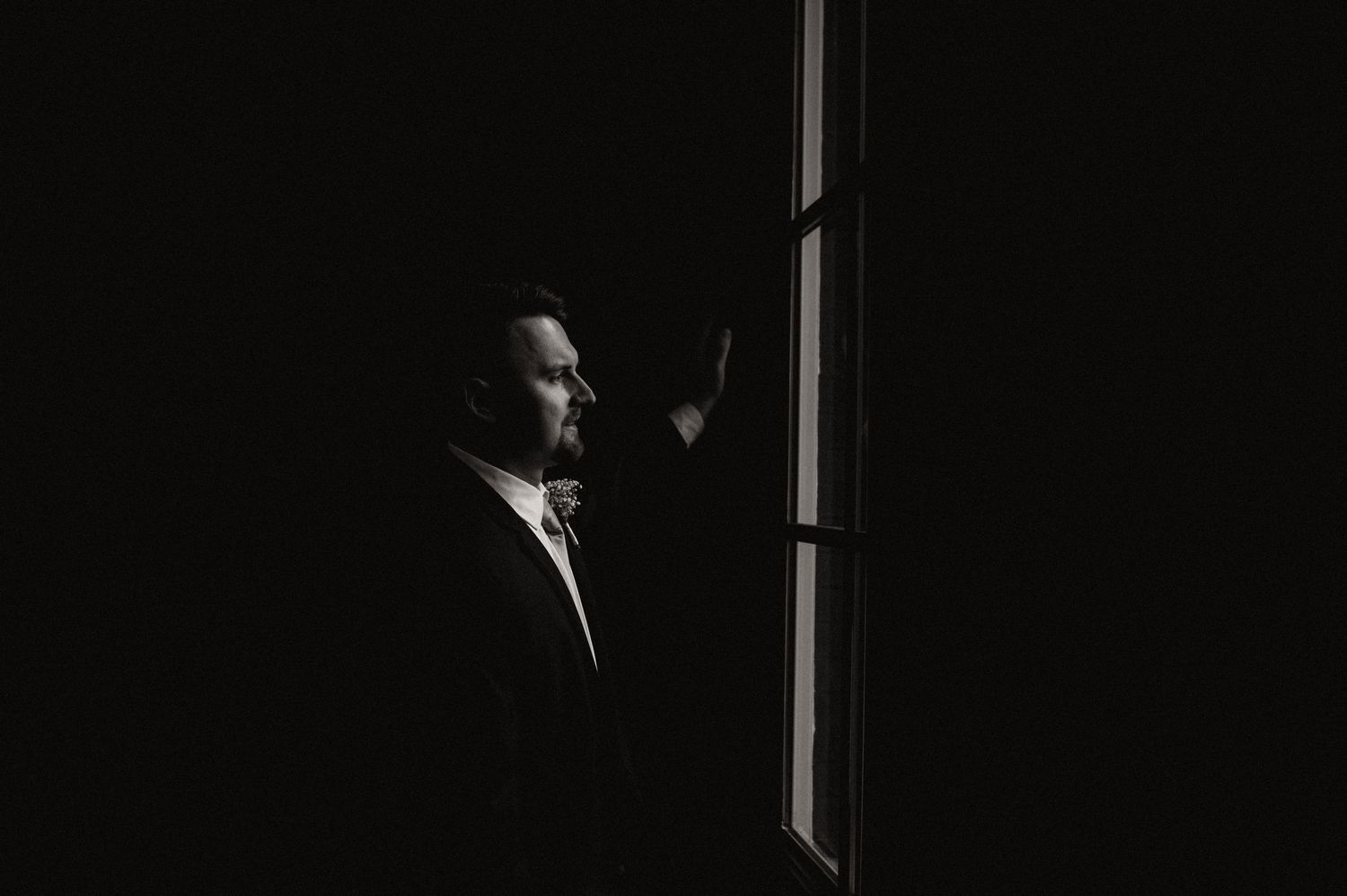 Dramatic side profile silhouette of a person in formal wear against window light.