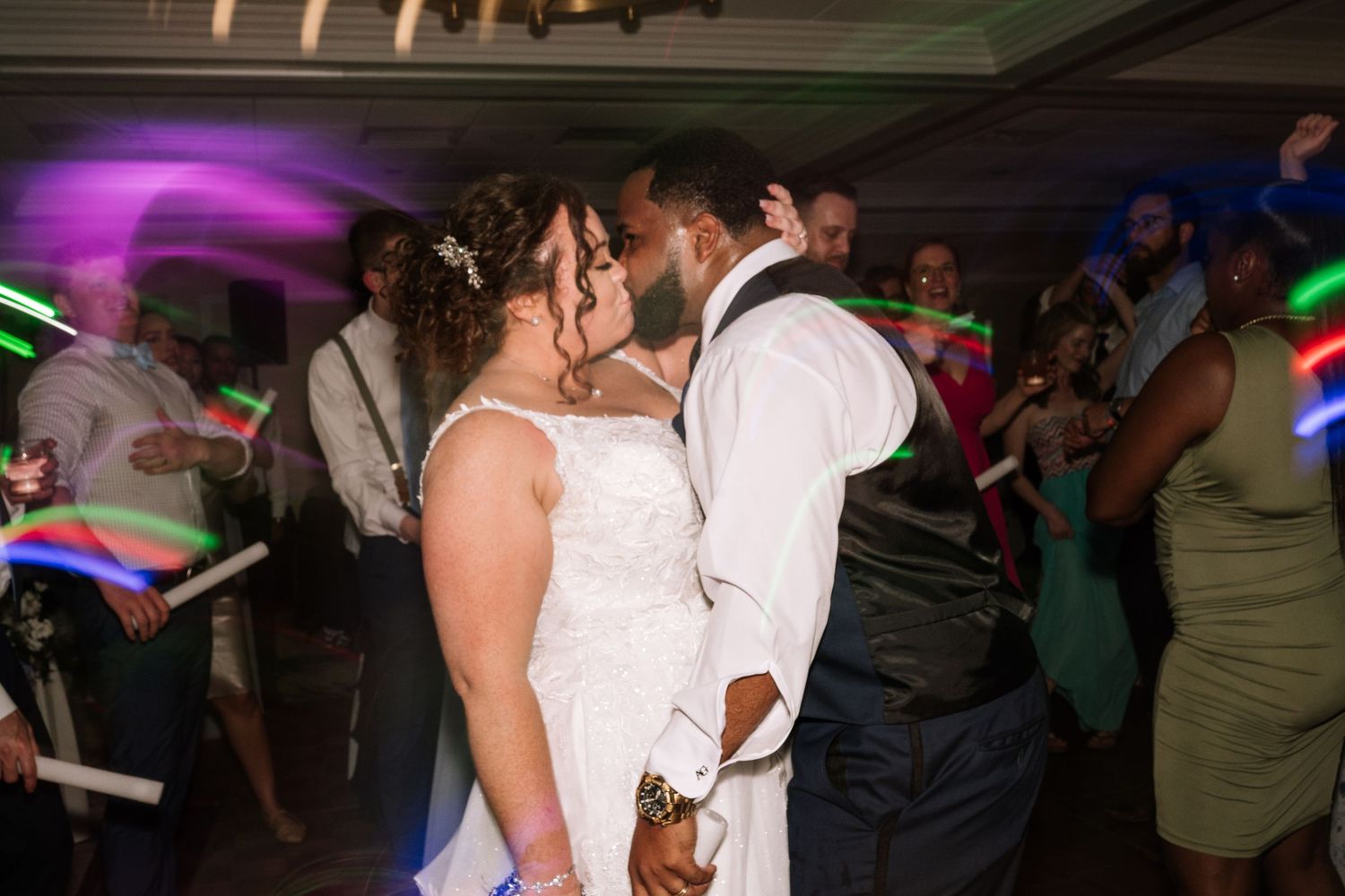 Wedding reception dance floor with colorful lights and glow sticks.