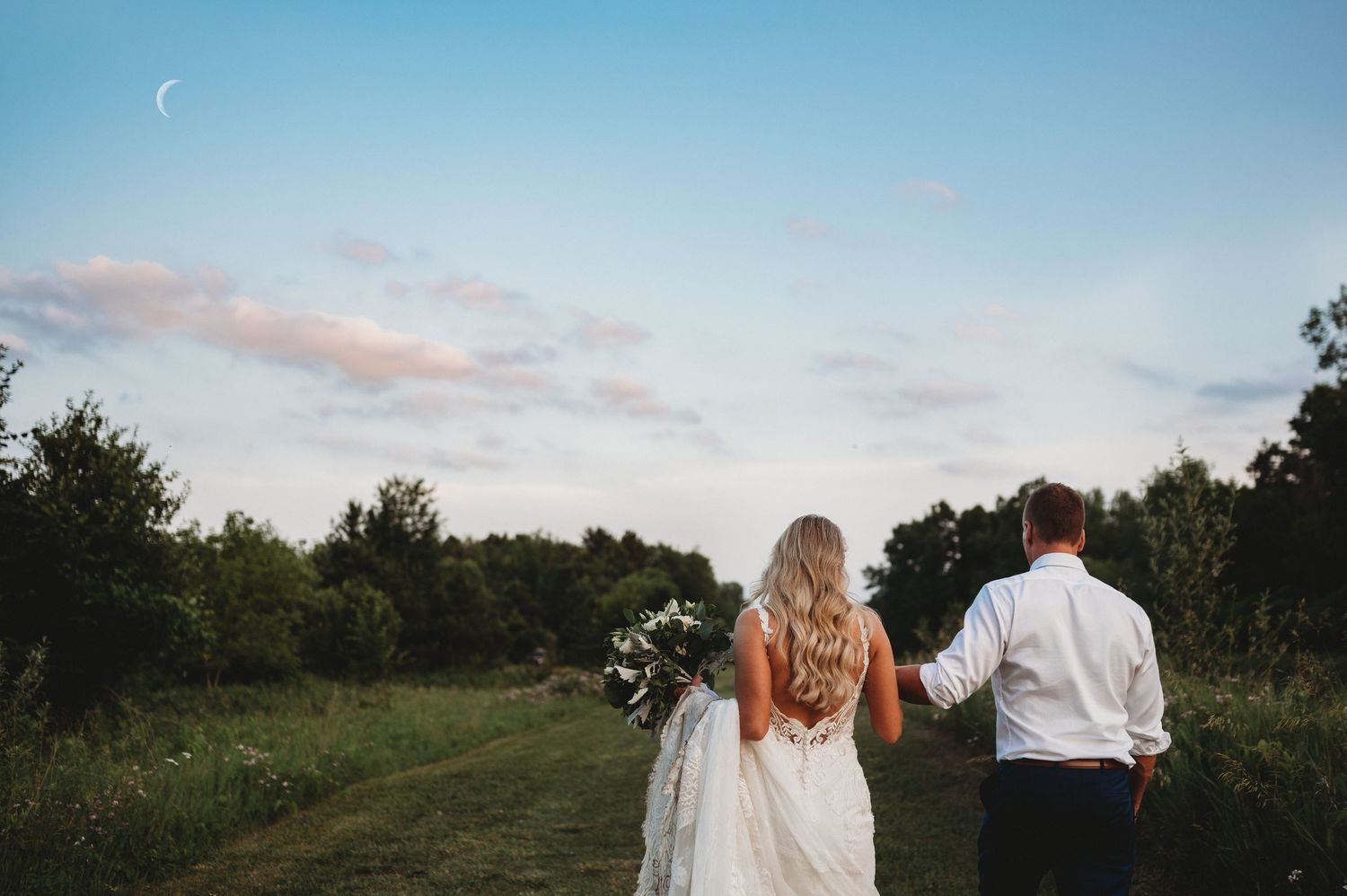 Couple walking hand in hand at sunset after their wedding ceremony.
