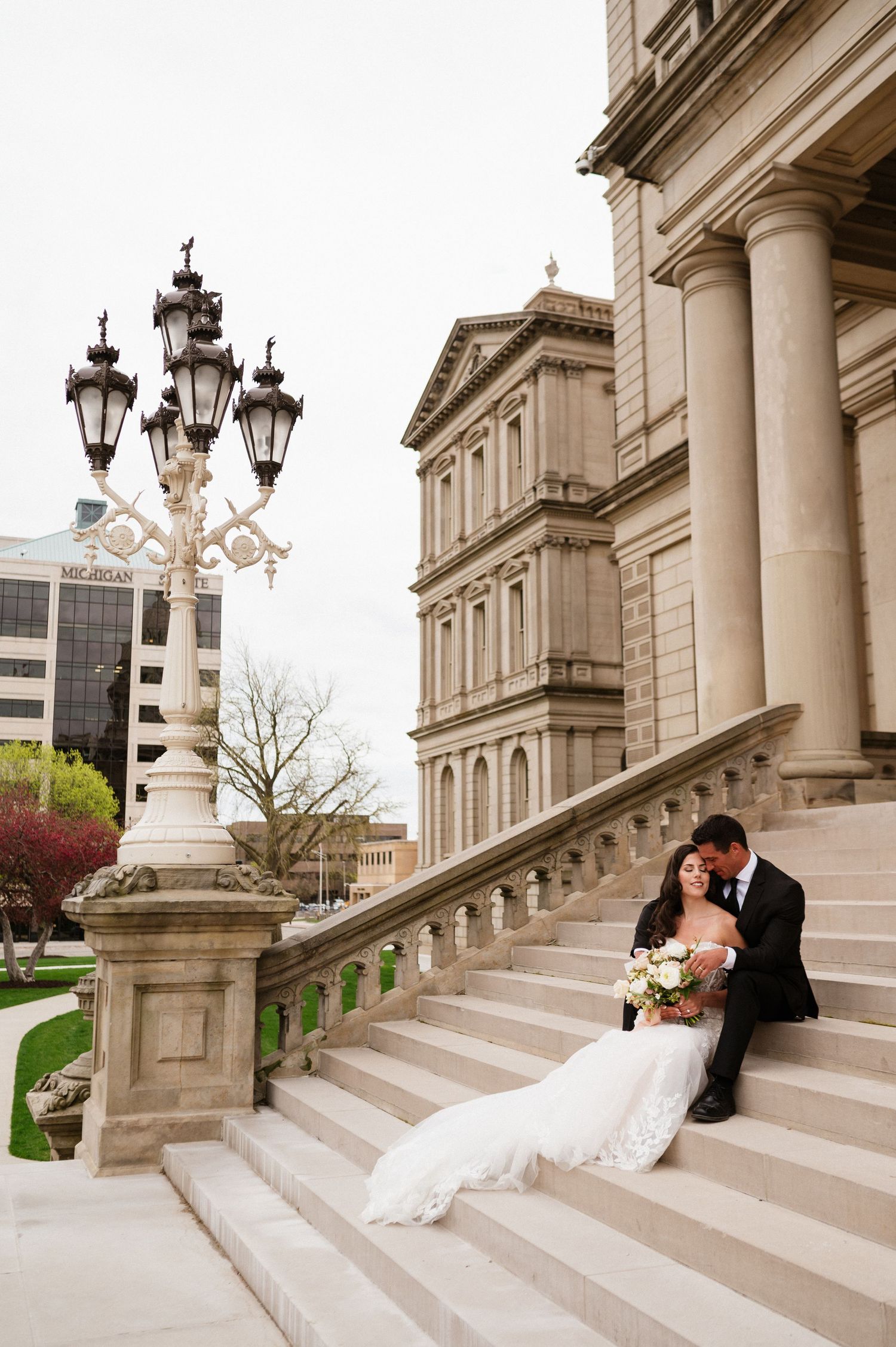 Newlyweds share an intimate moment on grand architectural steps.