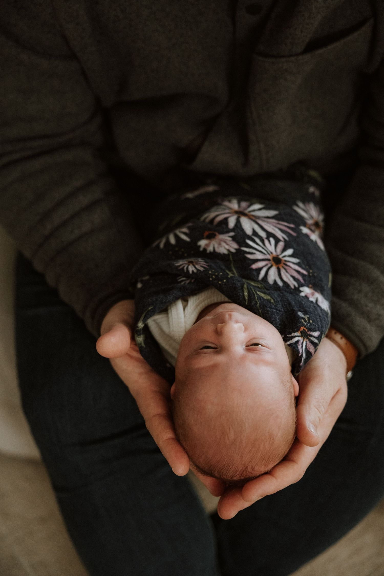Close-up view of a baby wearing a floral print outfit being cradled.