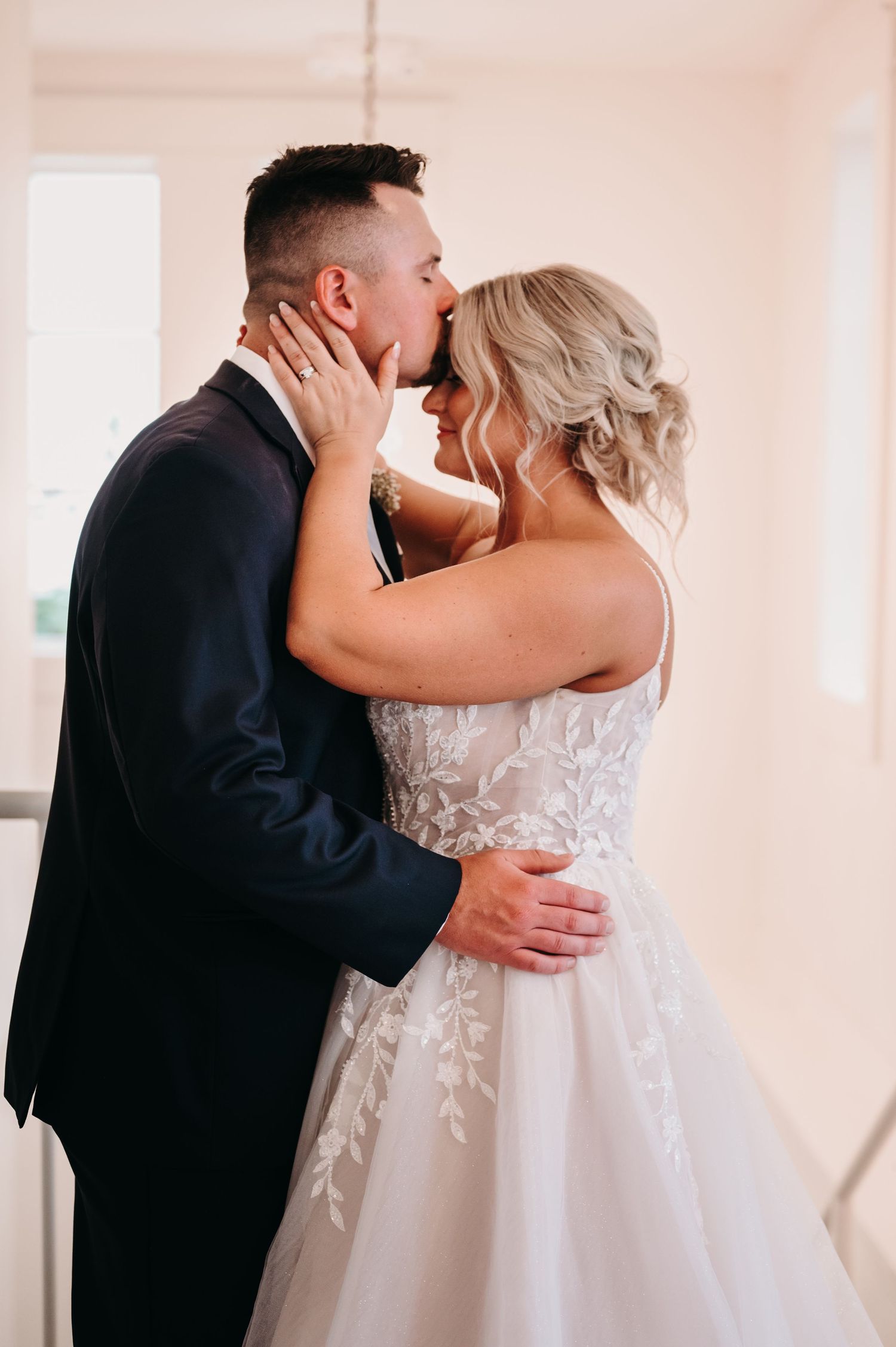 Romantic wedding moment as couple shares intimate kiss in front of elegant white doors.