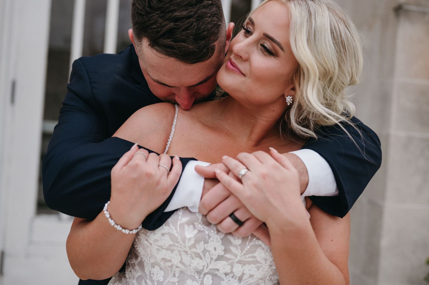 Intimate moment between newlyweds sharing embrace outside church.