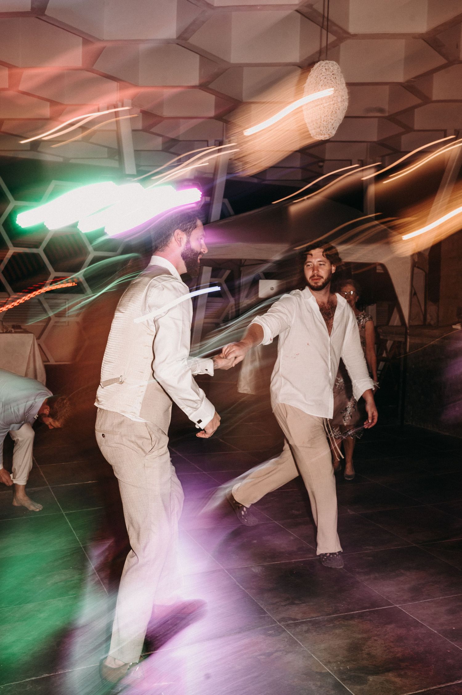 People dancing under colorful lights in a modern geometric venue.