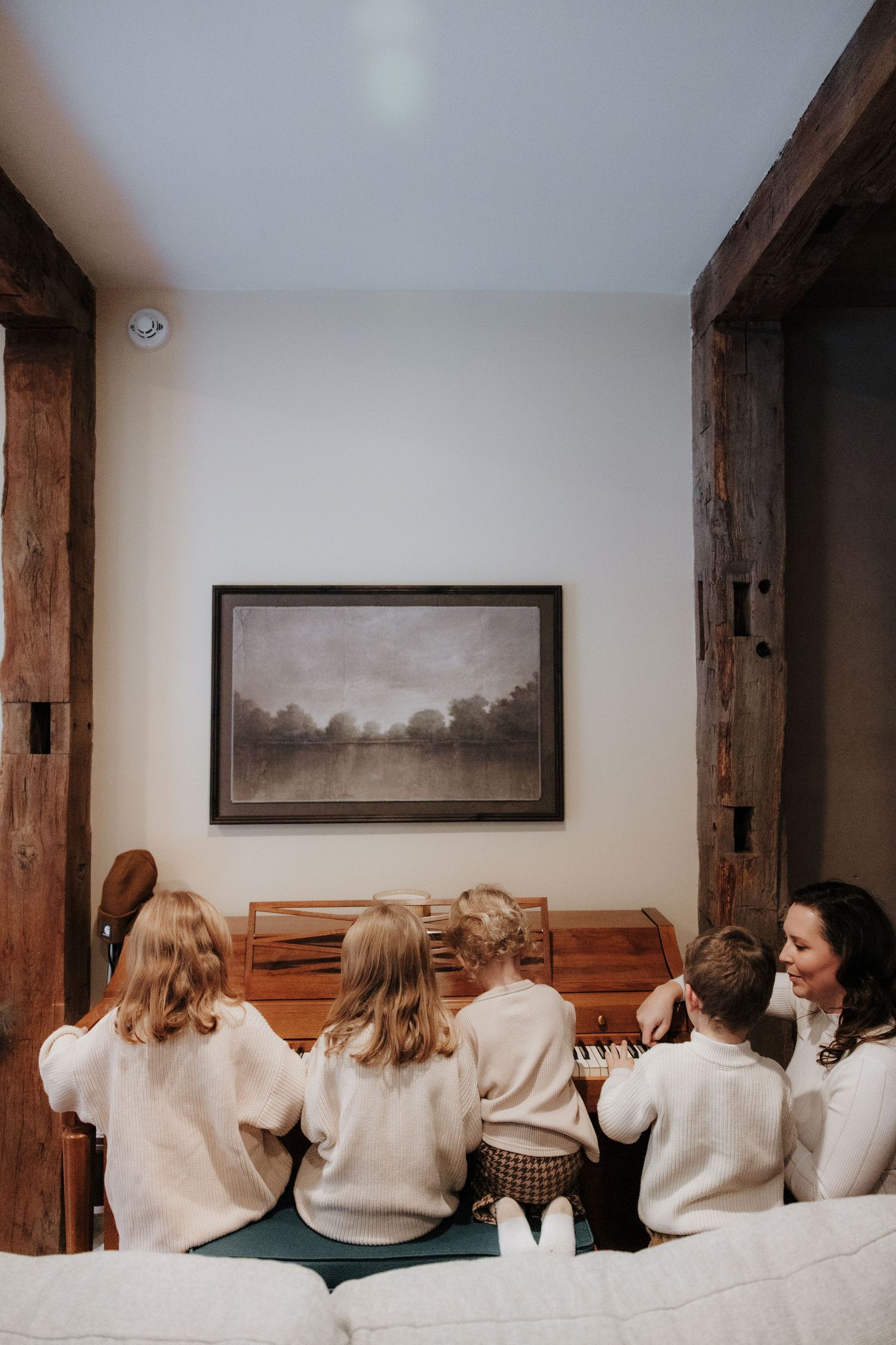 A row of people in matching cream-colored sweaters seated on a bench in an indoor setting.