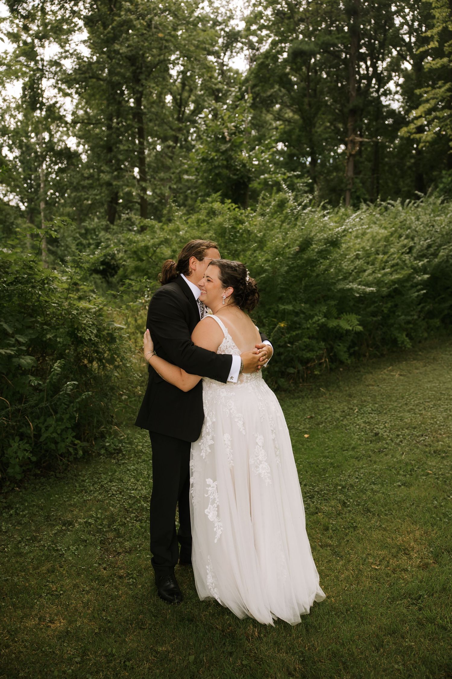 A couple shares an intimate kiss during their wedding photos in a lush garden setting.