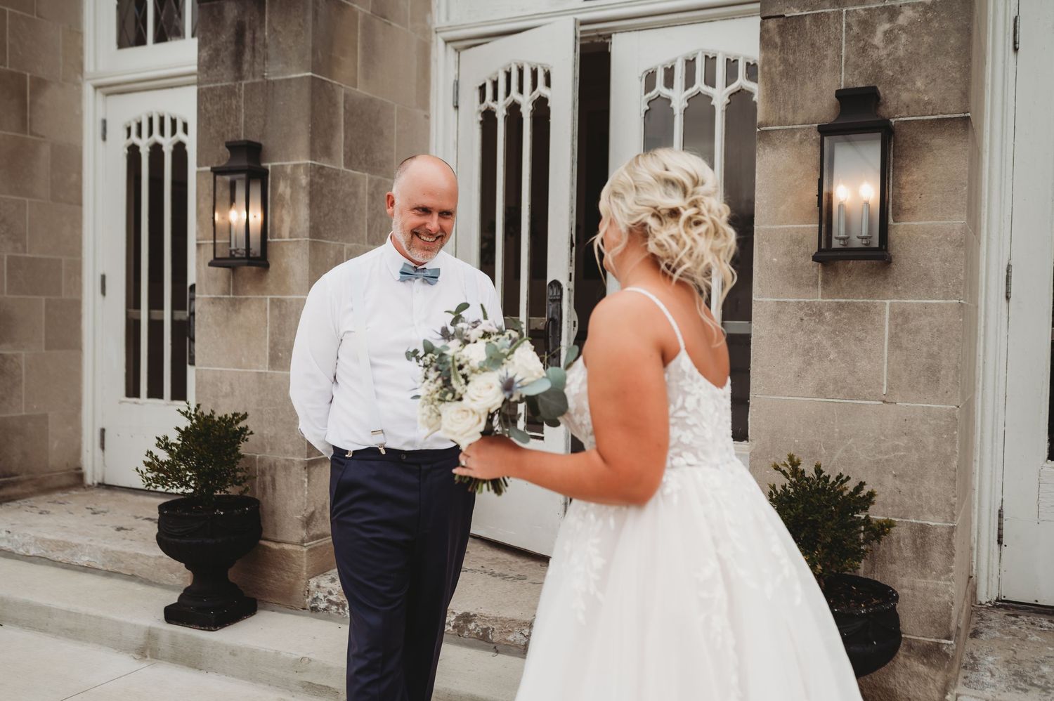 A tender wedding moment captured outside a stone church with ornate architectural details.
