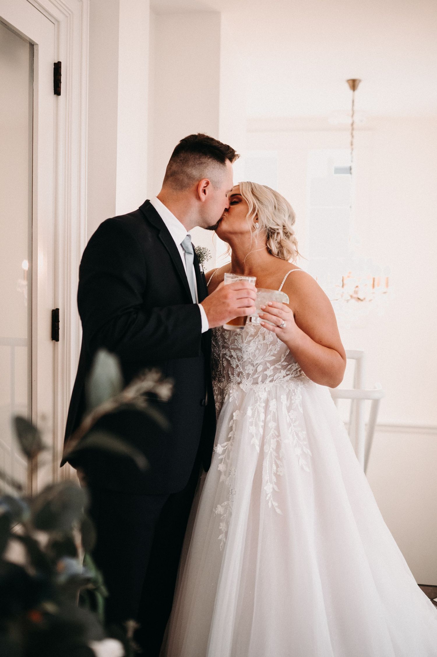 A romantic moment shared between a couple in formal attire against a bright white interior.
