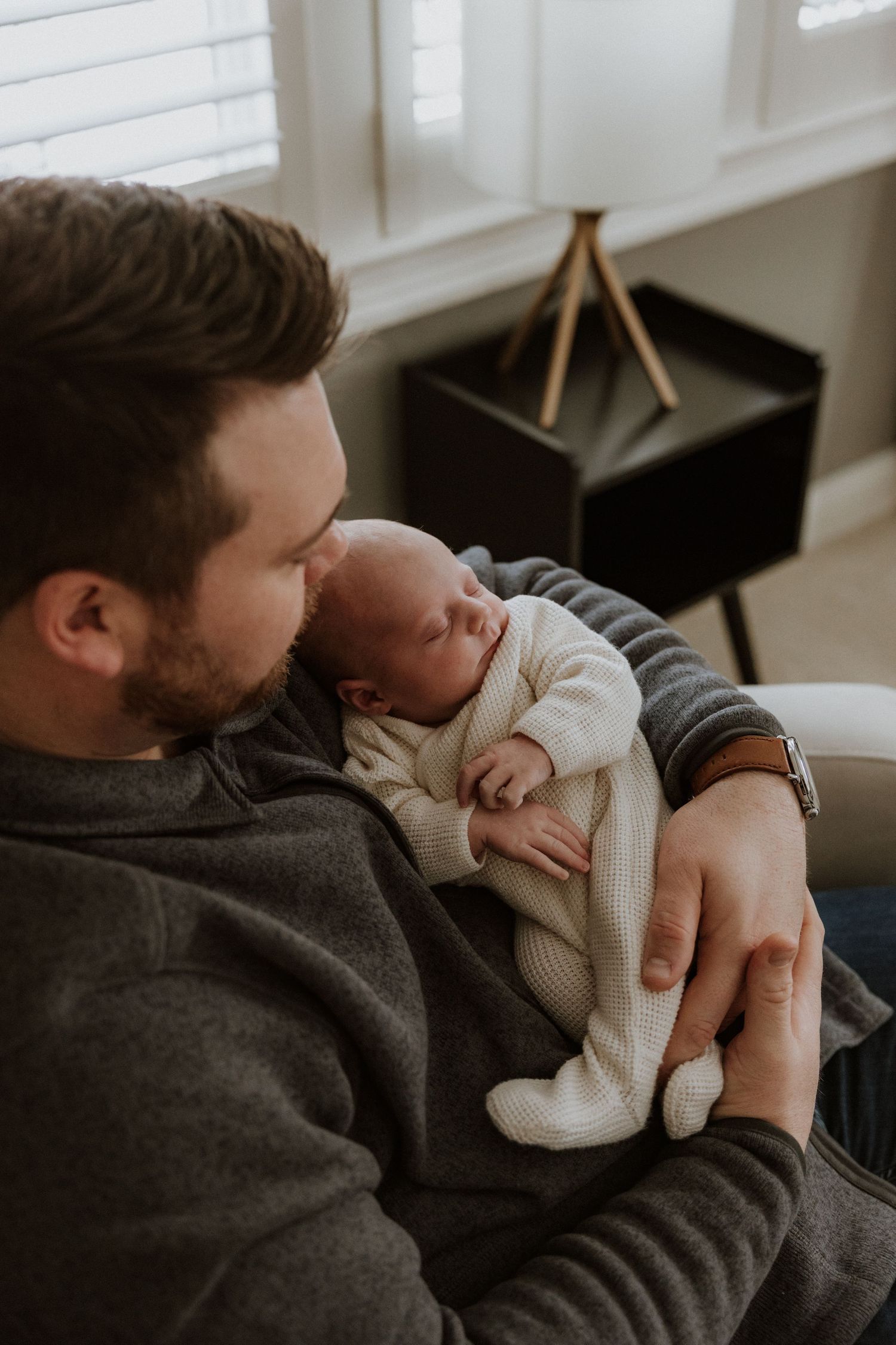 Intimate moment between parent and baby as they rest together on a cozy chair.