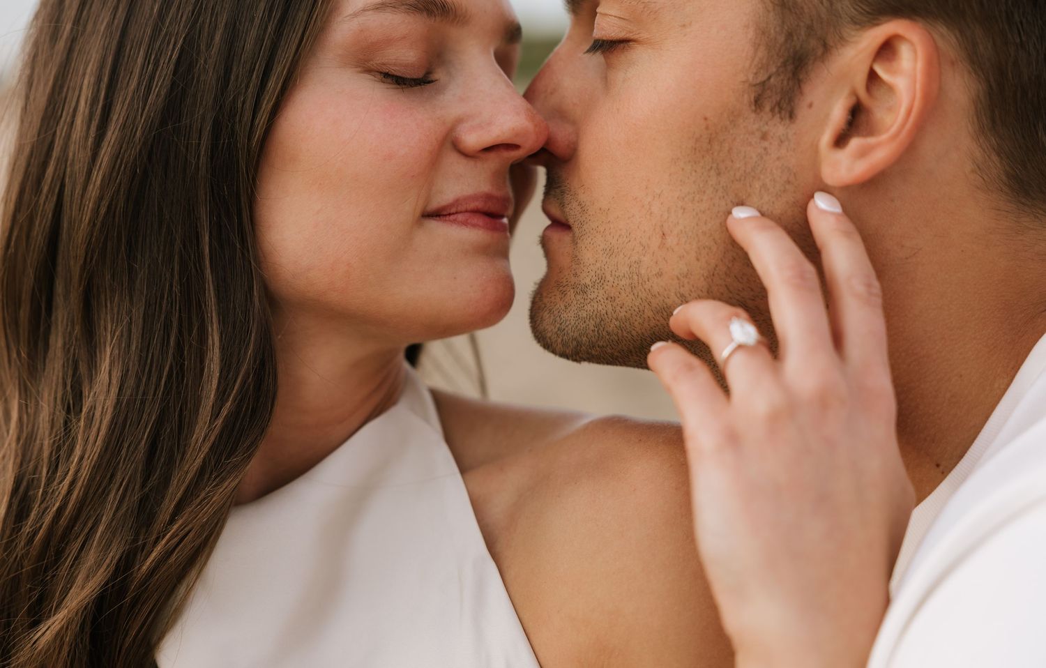 Close-up of a couple sharing a tender kiss, woman gently touching mans face.