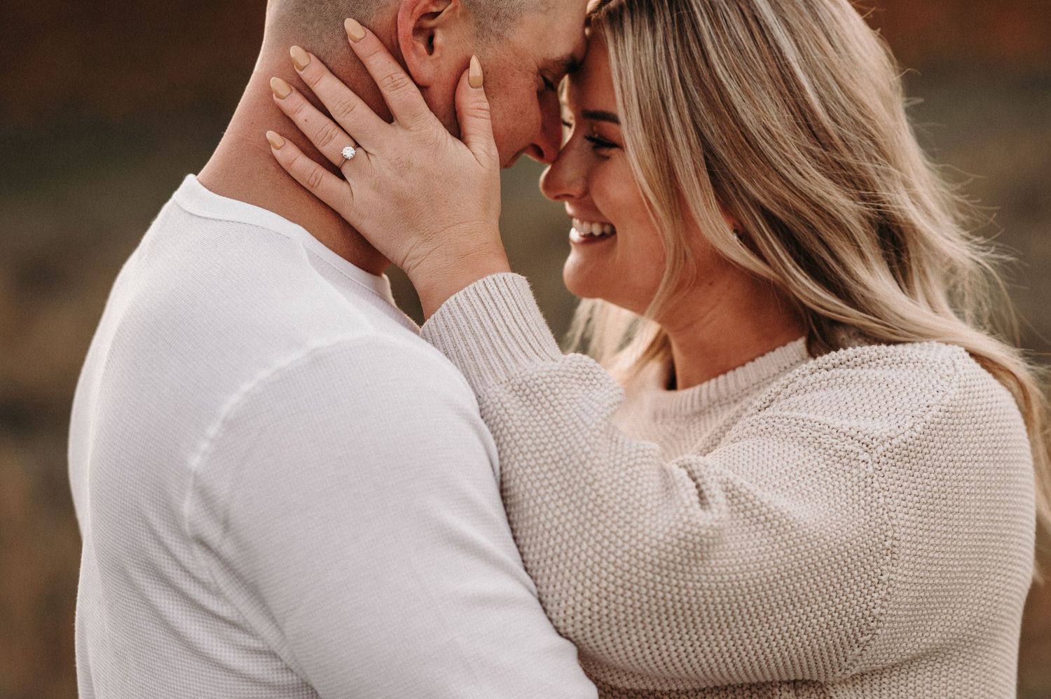 Intimate close-up of a couple in cream sweaters sharing a tender moment.