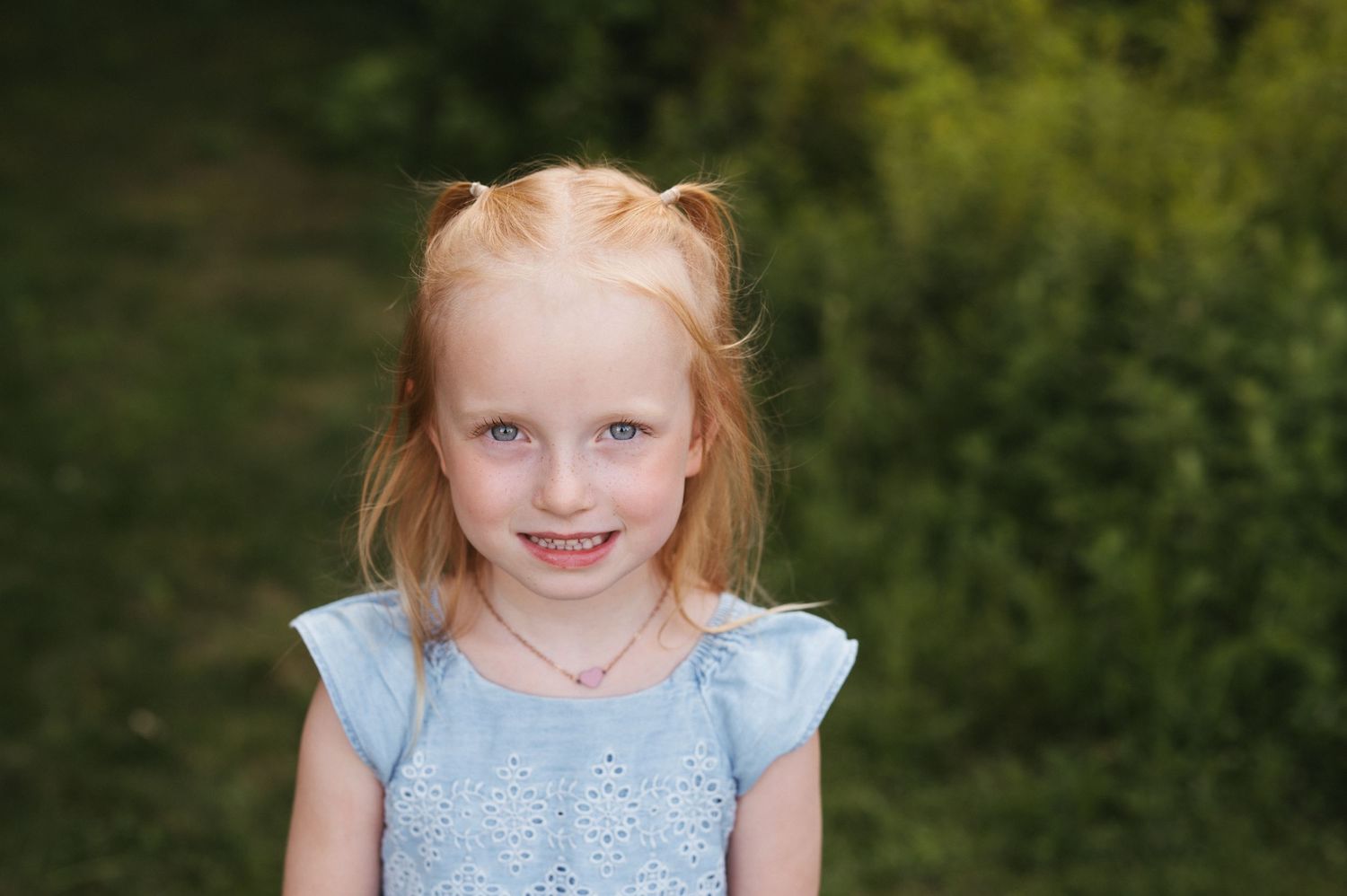 A close-up outdoor portrait featuring a light blue dress and natural lighting.