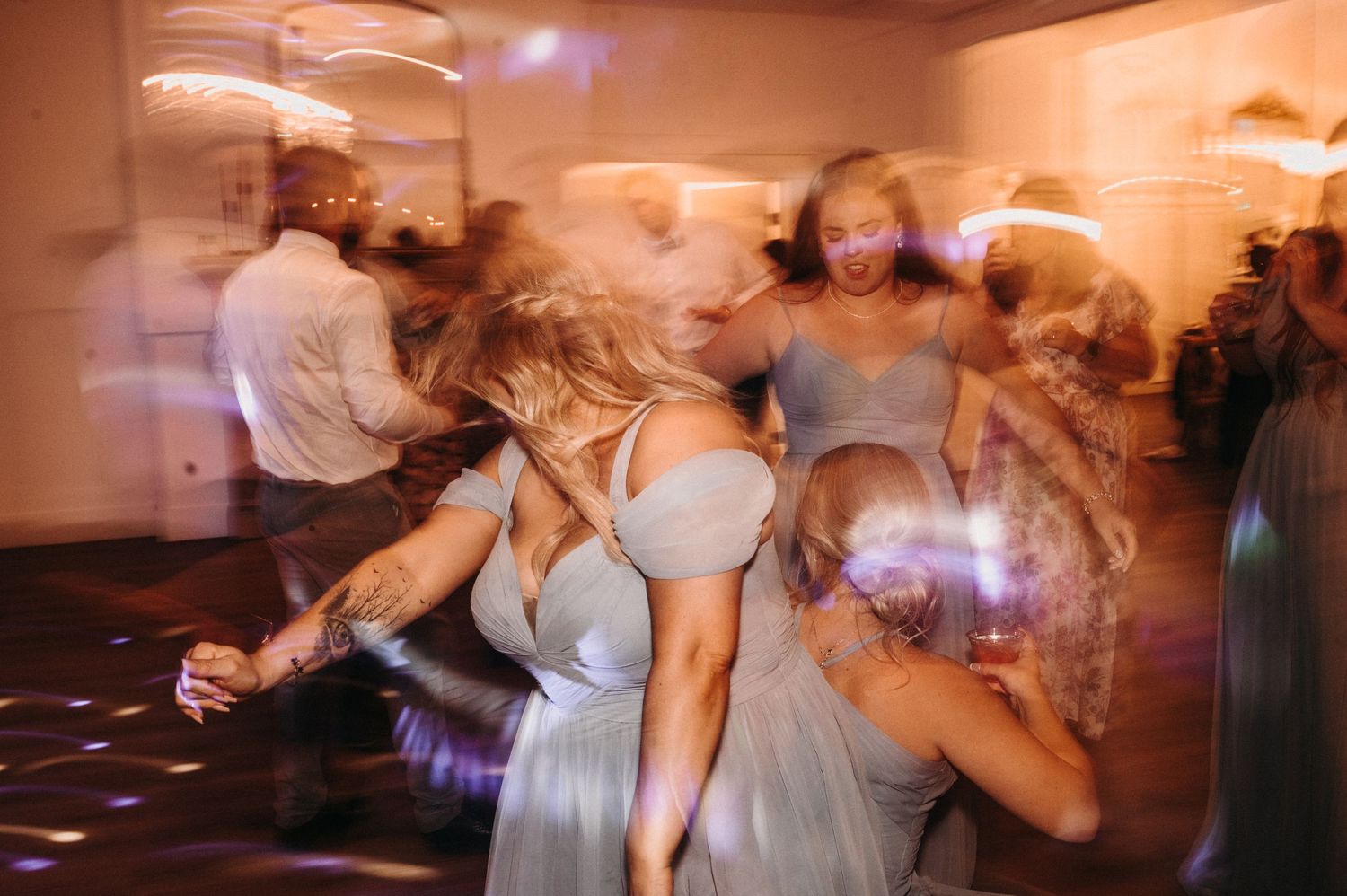 Dynamic dance floor scene with motion blur capturing the energy of wedding celebration.