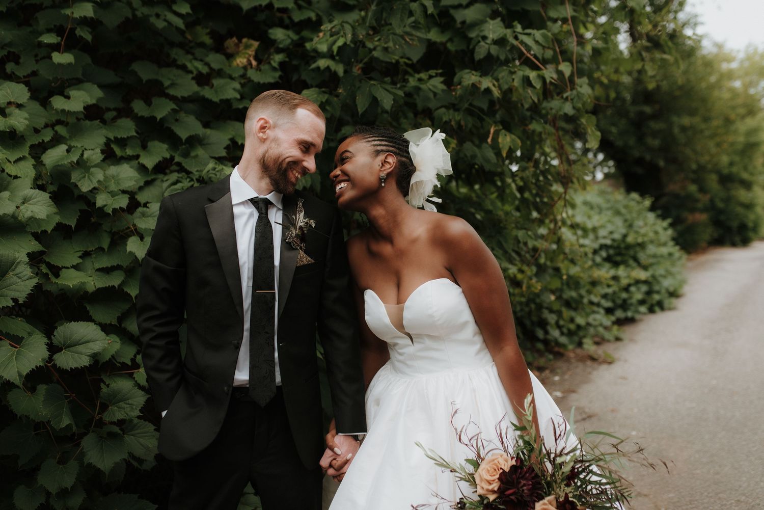 A couple shares an intimate moment outdoors surrounded by lush greenery.