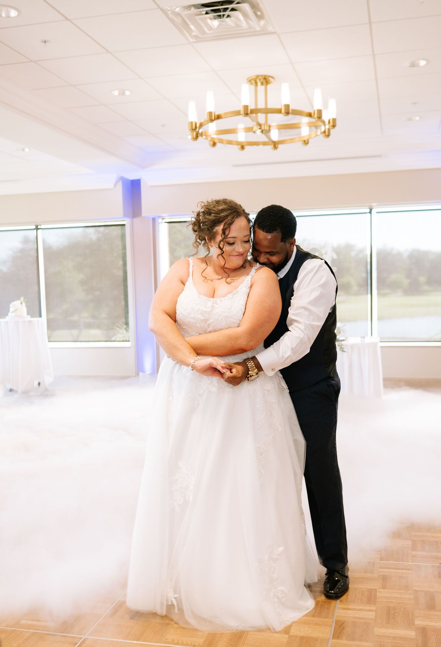 Wedding couple sharing intimate dance moments in an elegant reception hall with chandeliers.