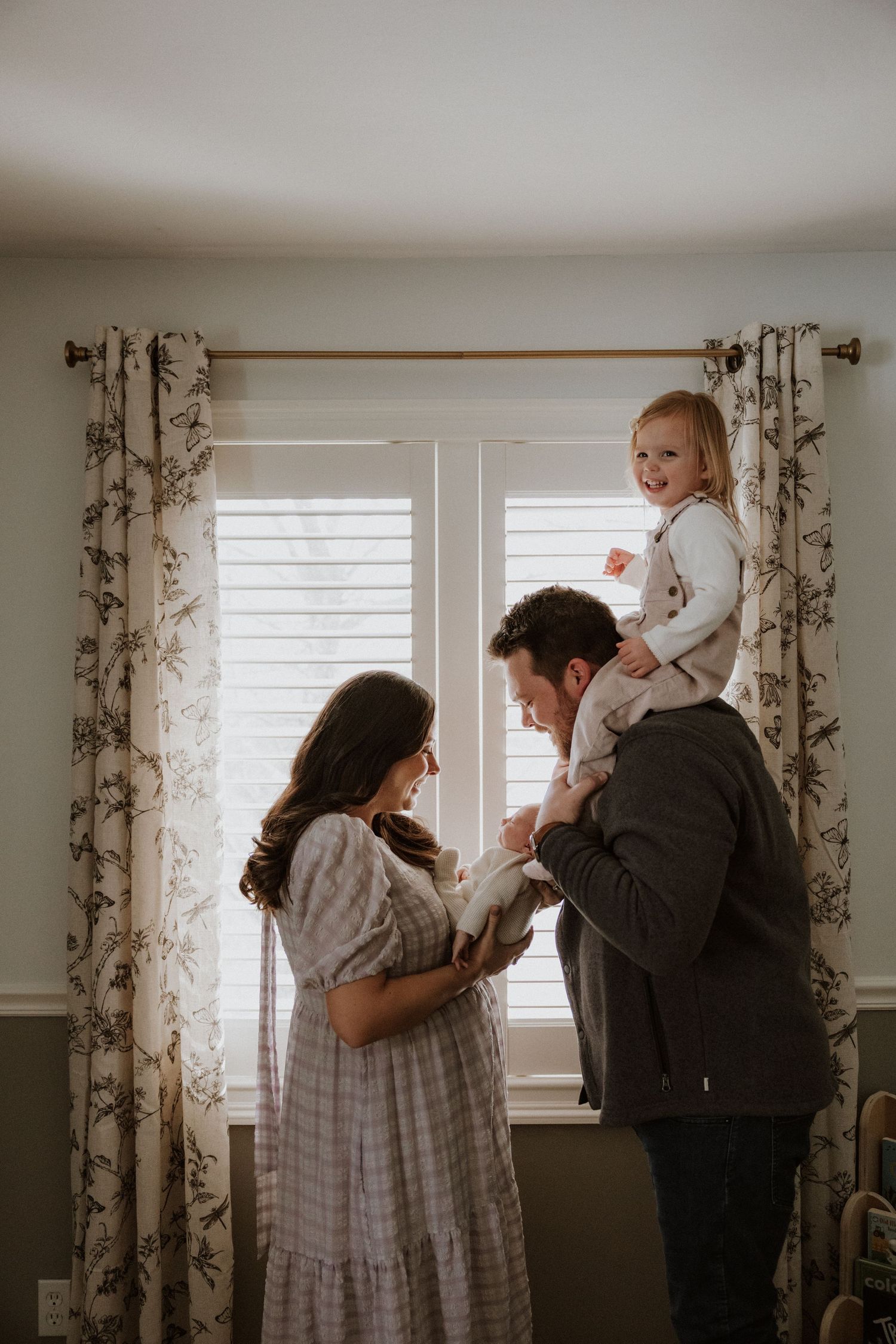 A bright nursery room with floral curtains and natural light showing family moments.