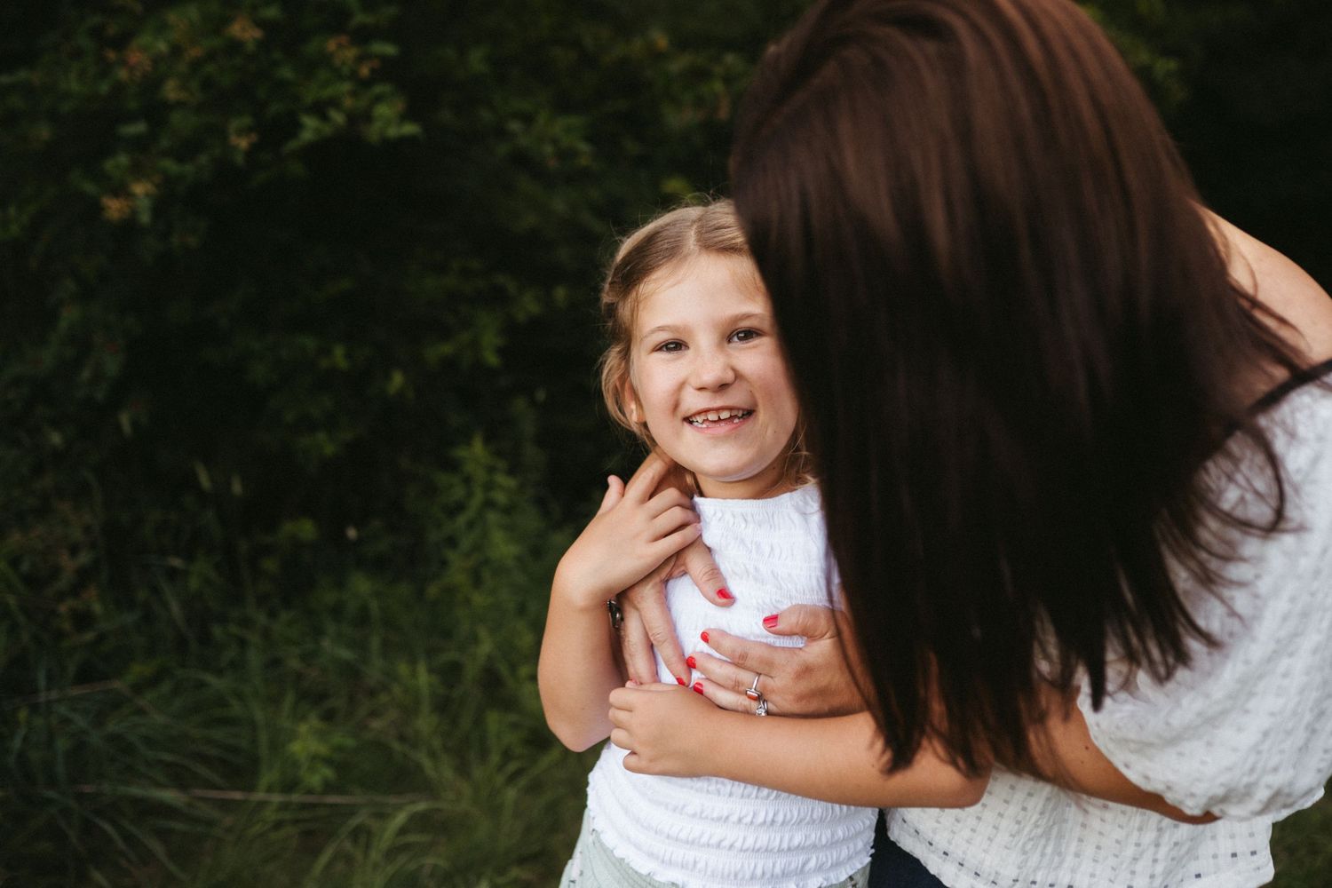 A candid moment of joy captured outdoors with lush greenery in the background.