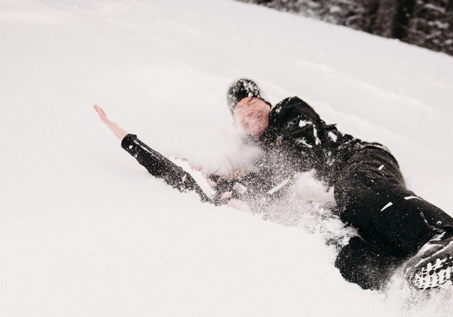 Person sliding down a snowy slope while covered in fresh powder snow.