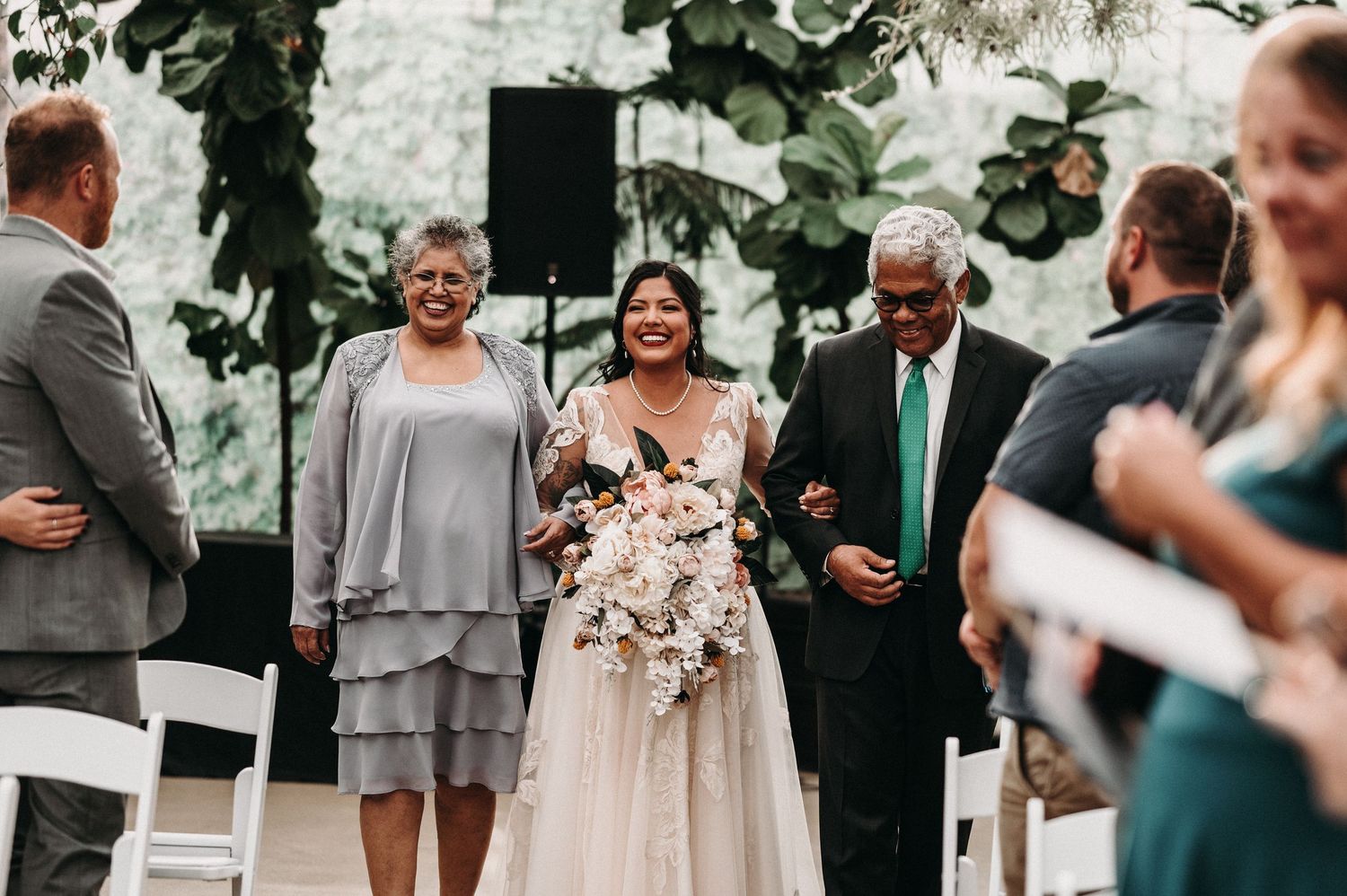 Wedding ceremony moment captured indoors with floral arch and guests in attendance.